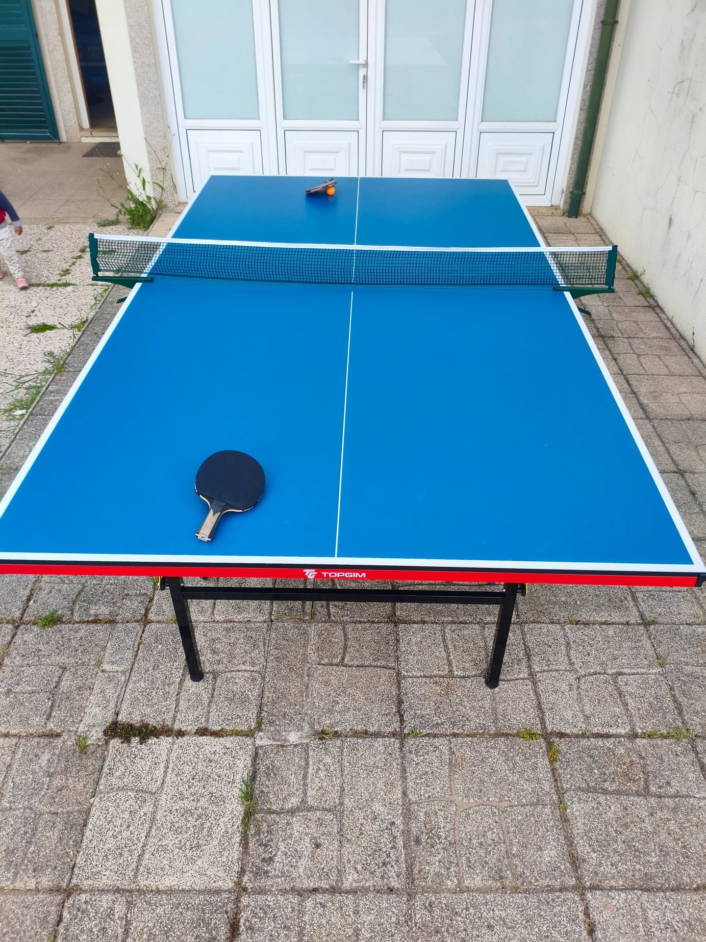 Mesa de ténis TOPGIM Training aberta no exterior com raquete e bola — vista aérea