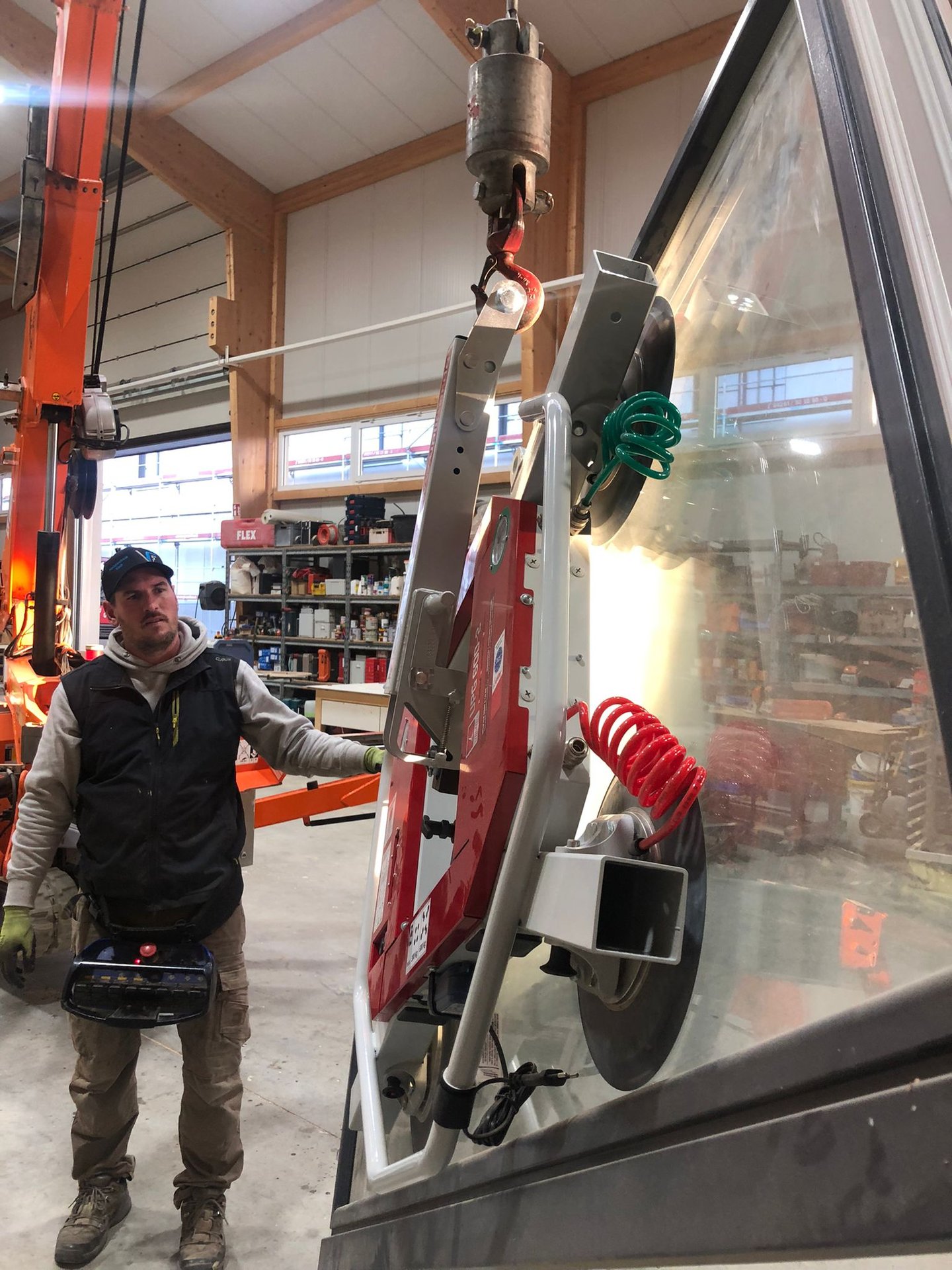 Schreinermeister Ferdinand Volk mit Glasscheibe am roten Vakuum-Saugheber in der Halle.