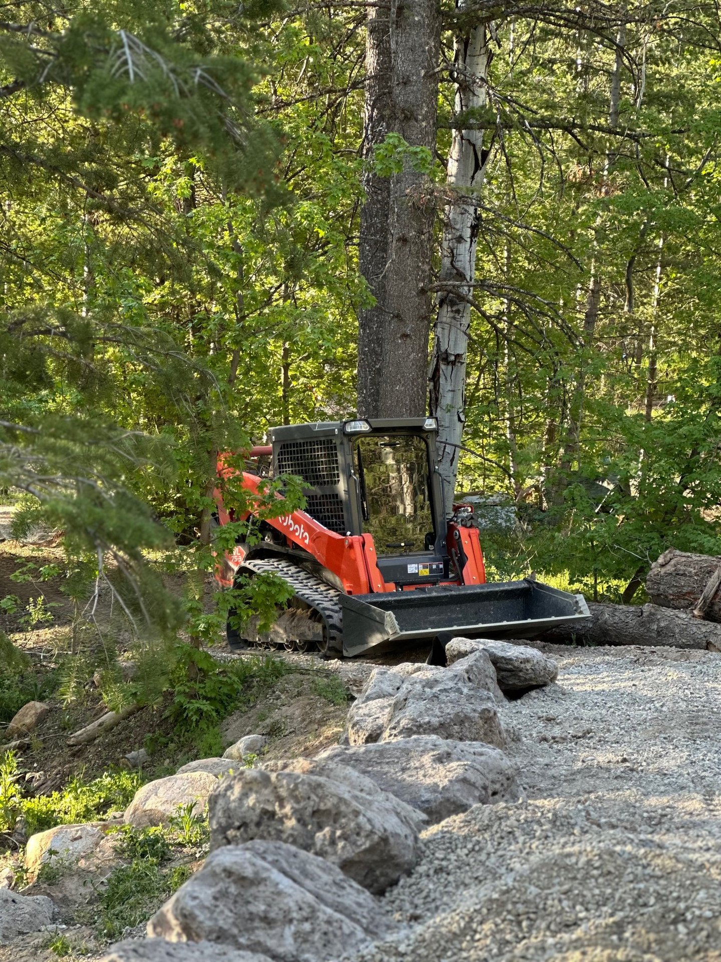 Kubota skid steer working on a boulder wall and grade work in northern utah