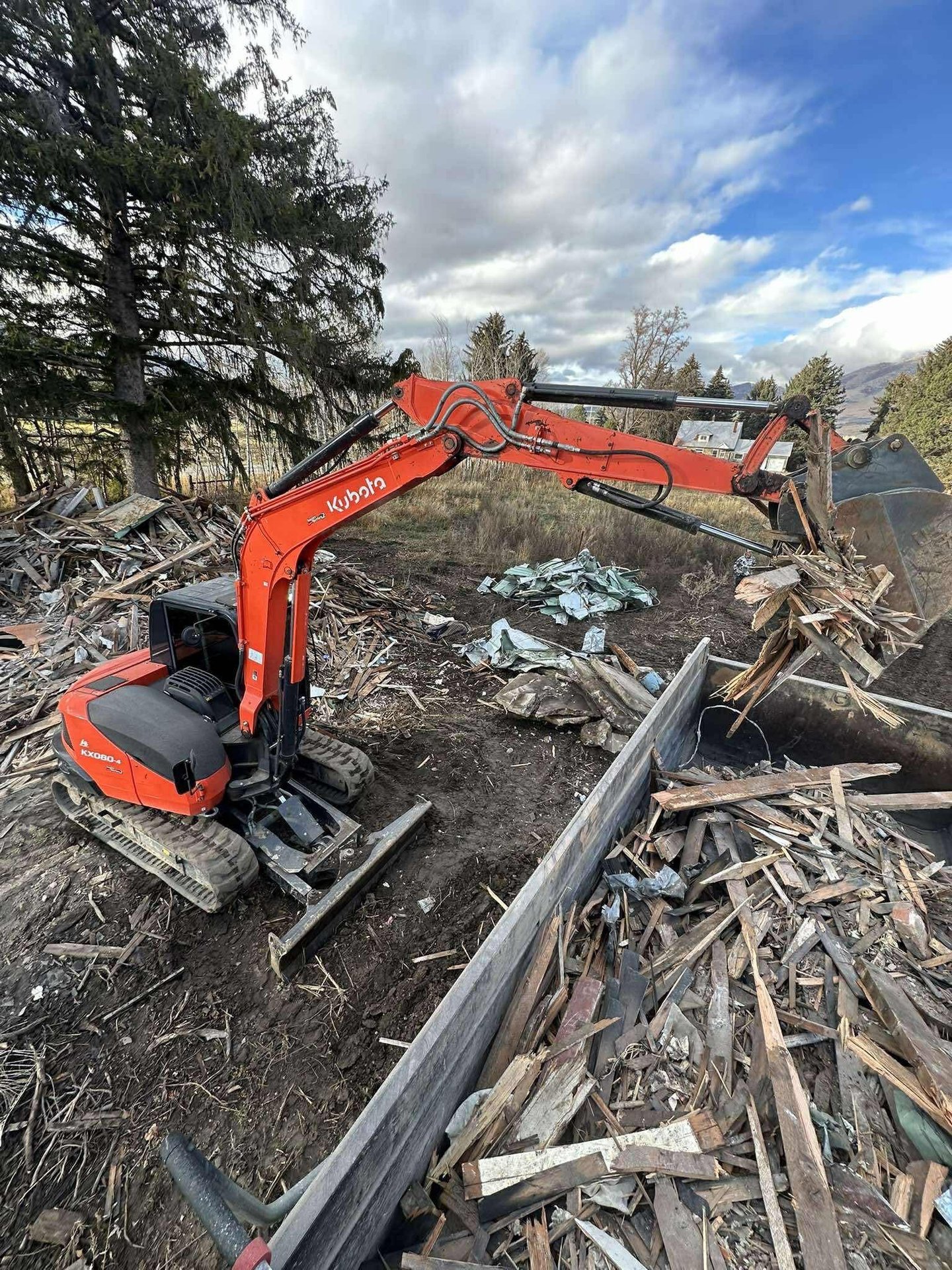 Kubota excavator loading demo debris into a dump trailer