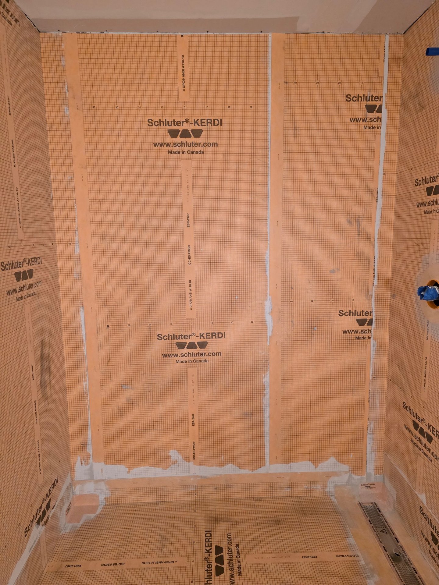 Schluter Kerdi waterproofing membrane installed on shower walls and floor for tile preparation.