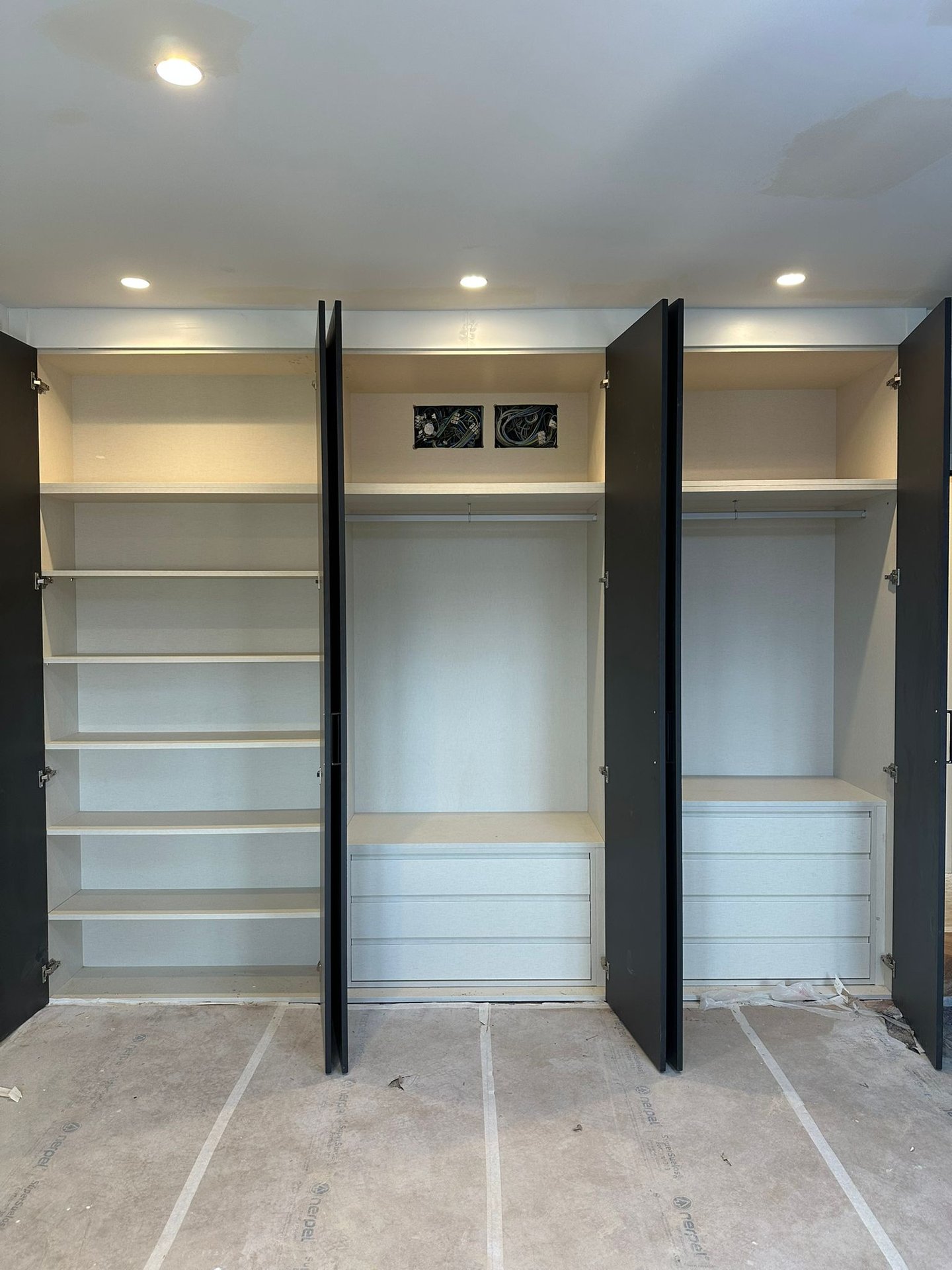 Armario abierto, tres secciones, estantes, cajones, barras.