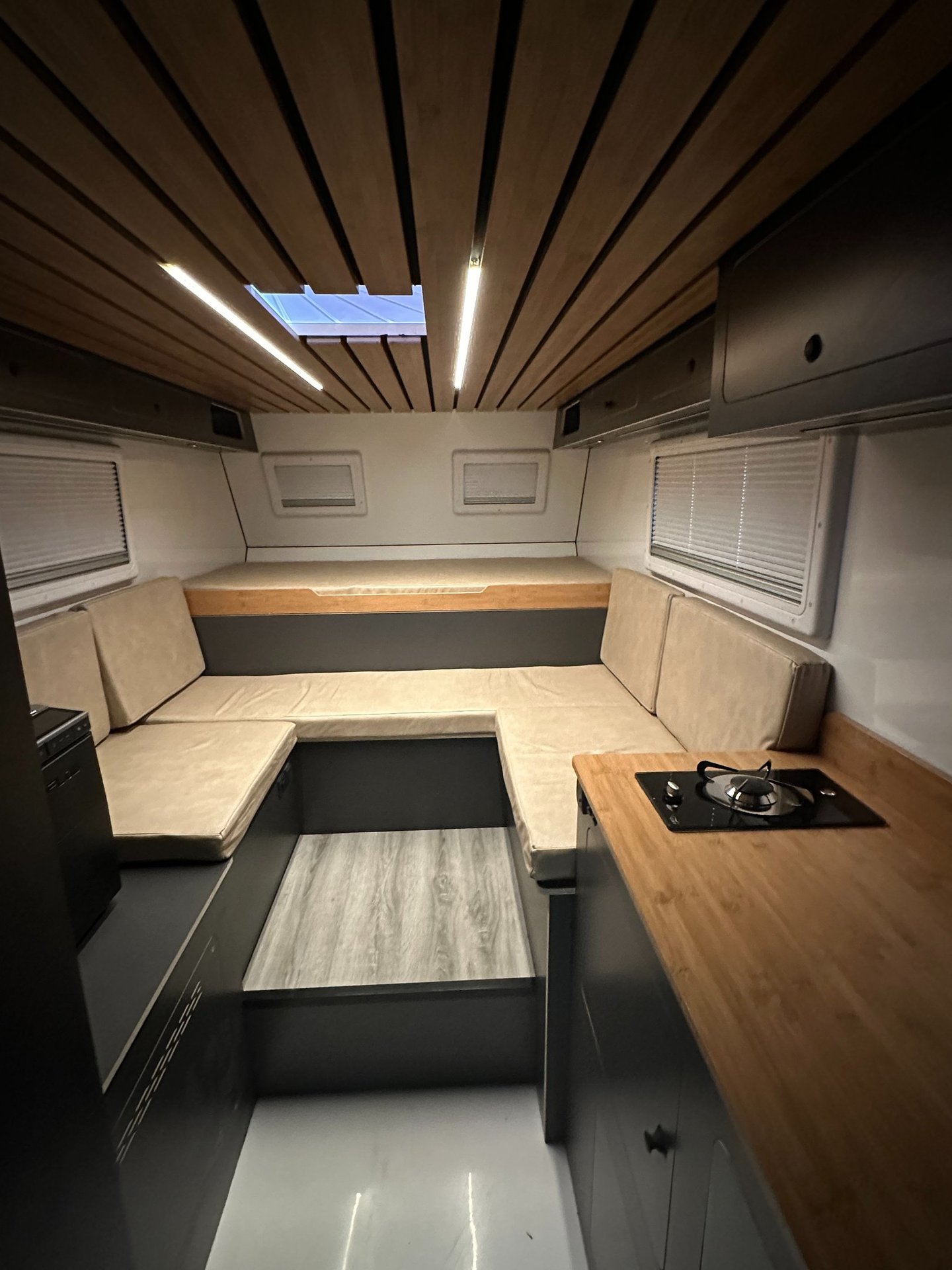 salón interior de una célula camper con luces led, cama y sofas