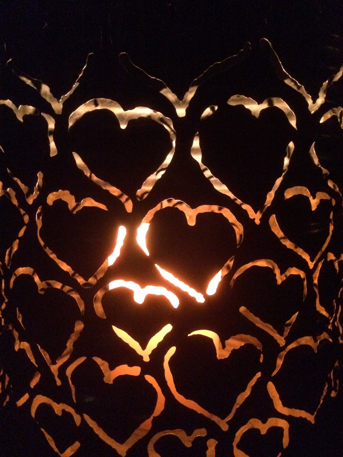 Warmes Kerzenlicht scheint durch Metallherzen und symbolisiert Wärme und Verbindung.