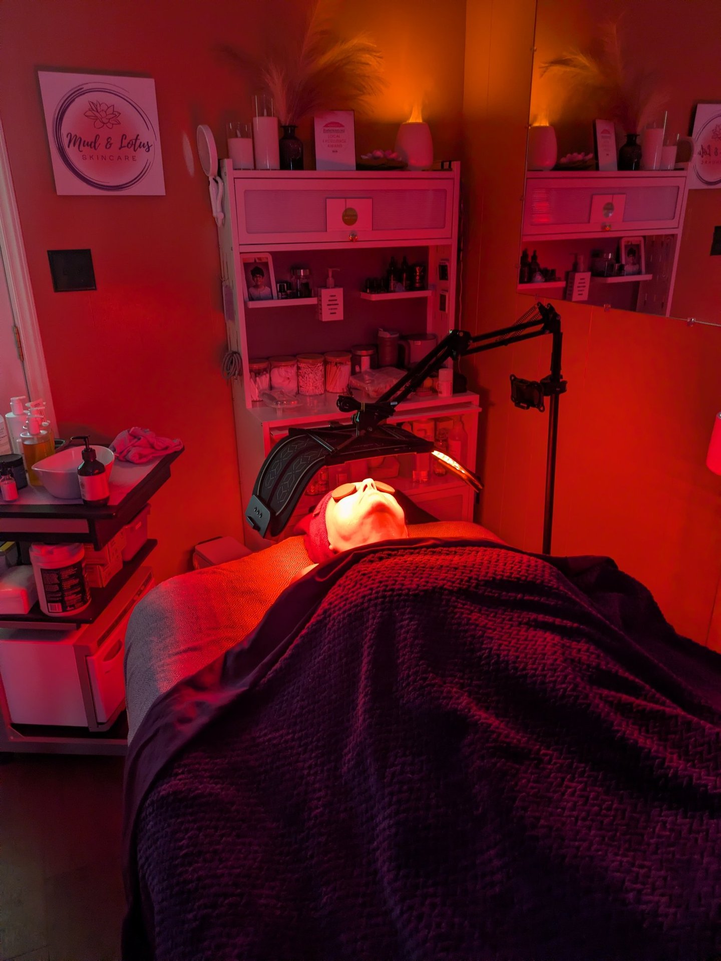 woman under a red LED light during a facial
