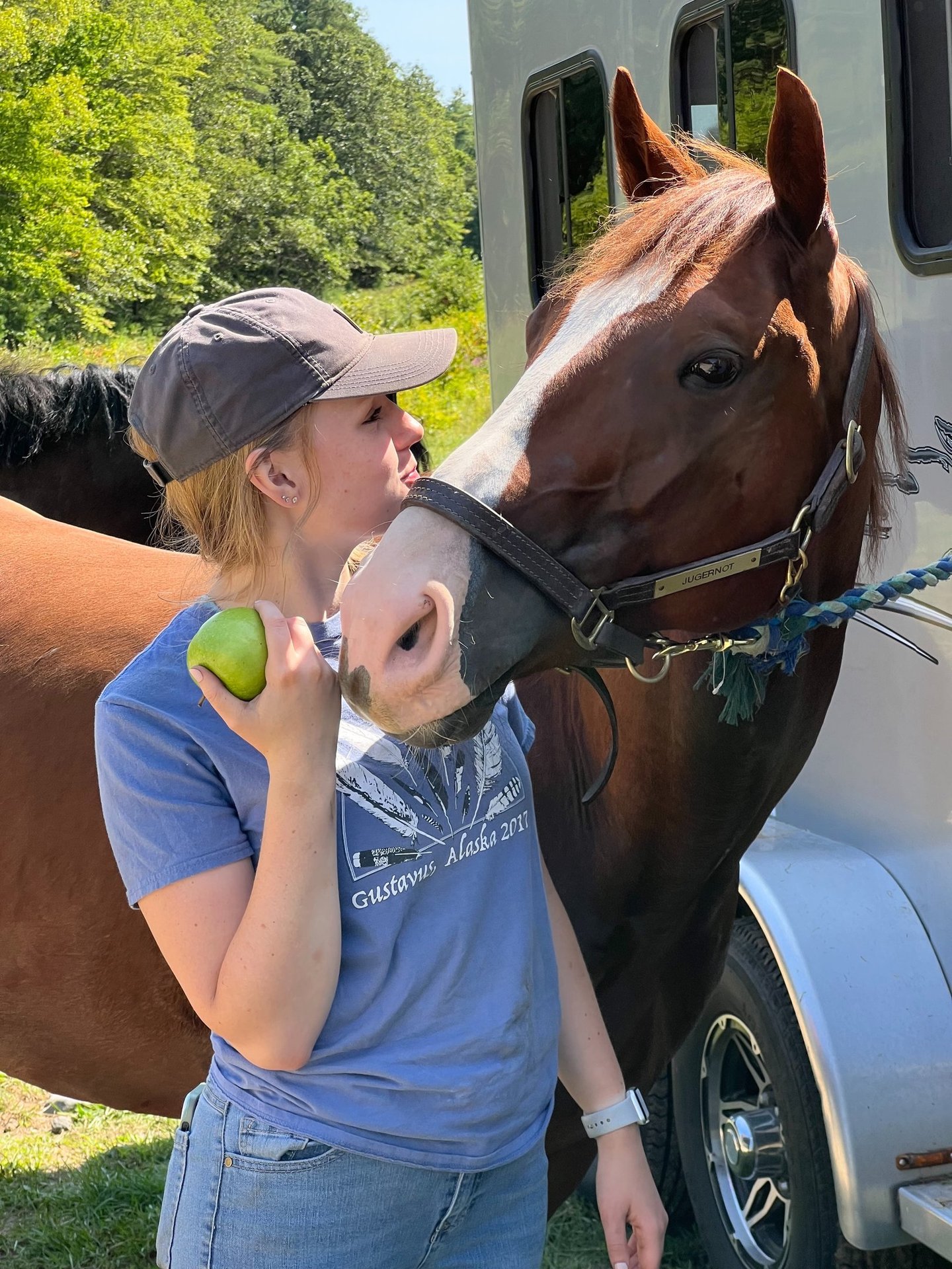 a woman in a hat and a horse at a trailer