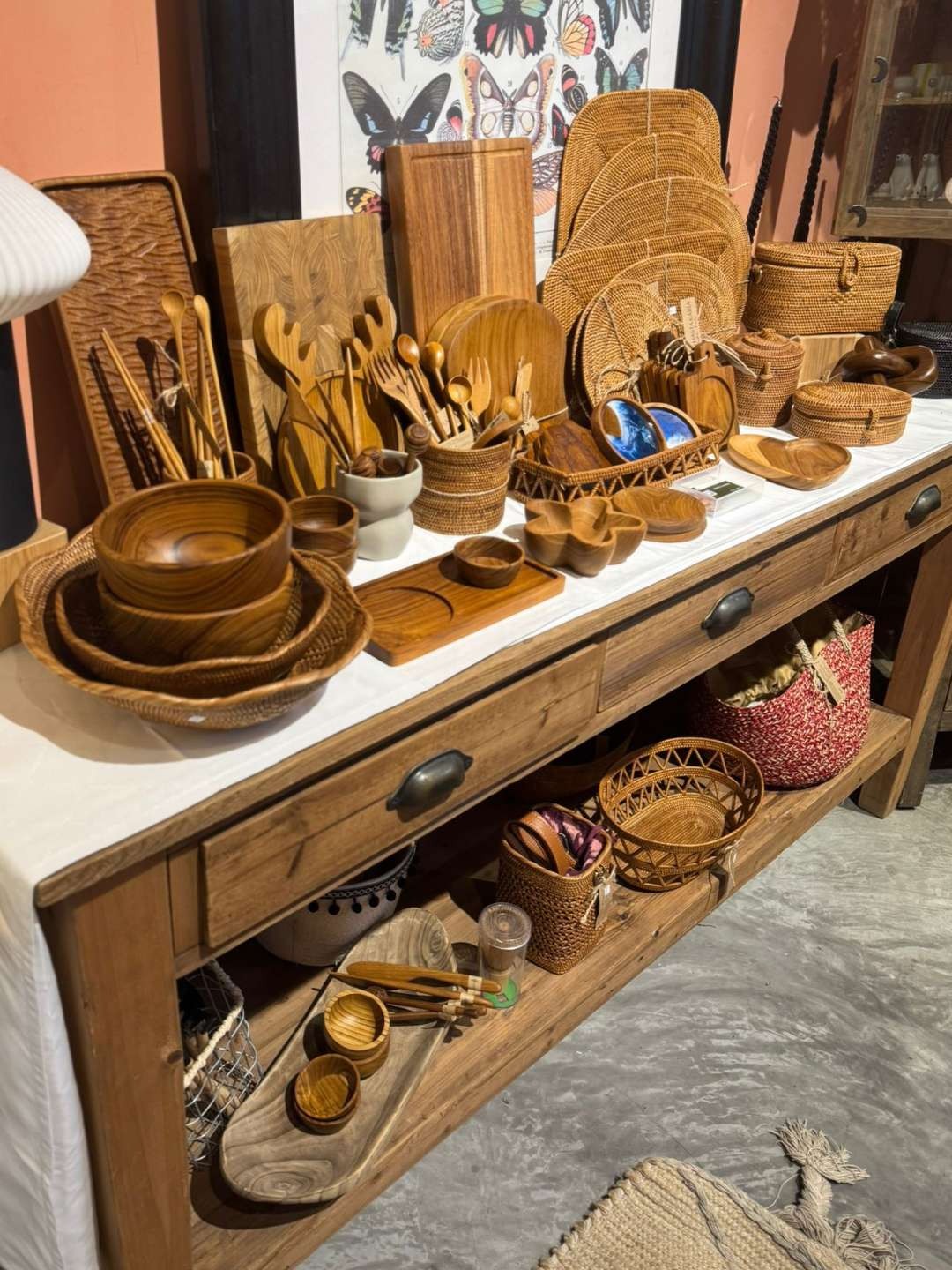 Wooden kitchenware and woven rattan baskets displayed on a vintage wood table.