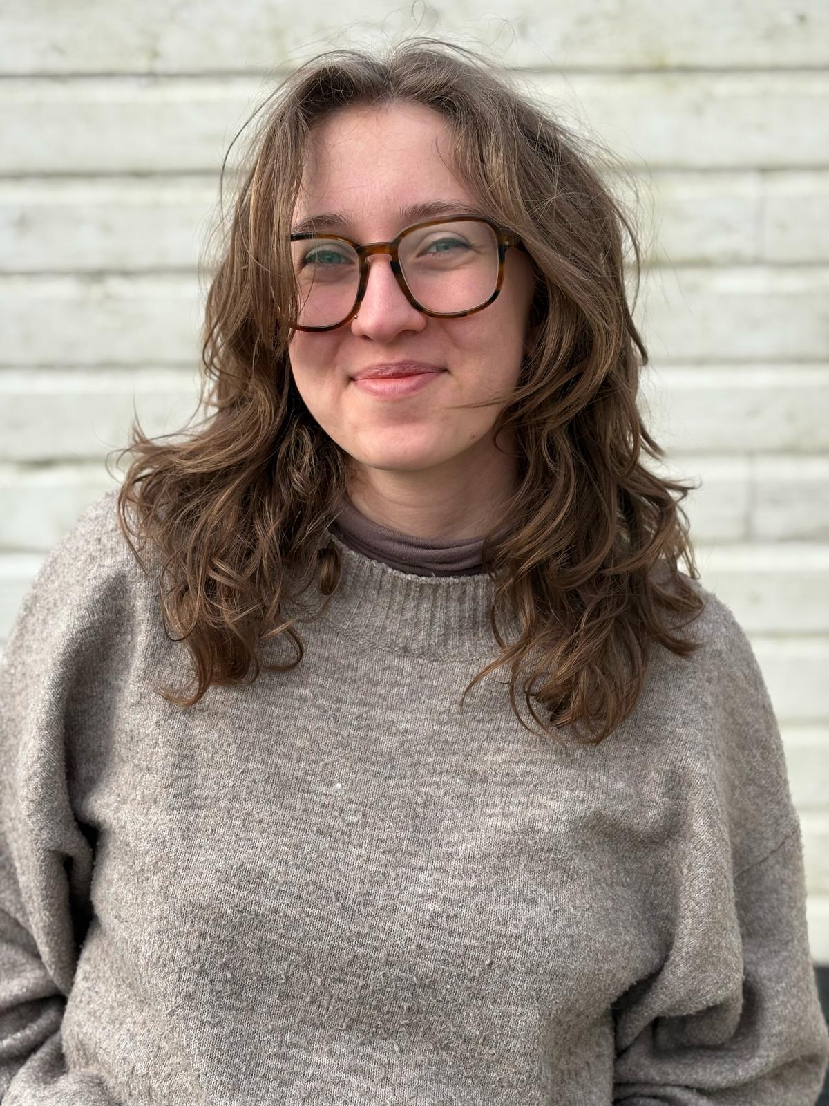 junge Hebamme mit Brille und gewellten Haaren