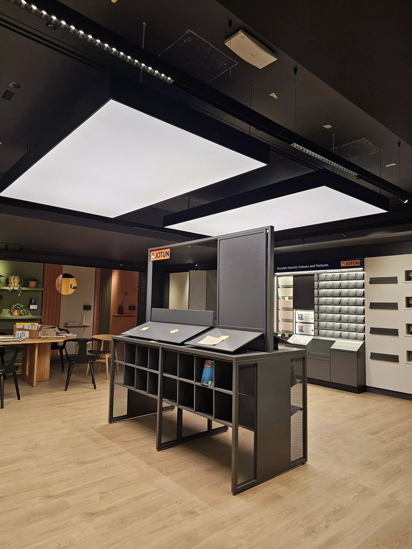 Modern Jotun paint showroom with backlit ceiling panels, color displays, and industrial shelving.