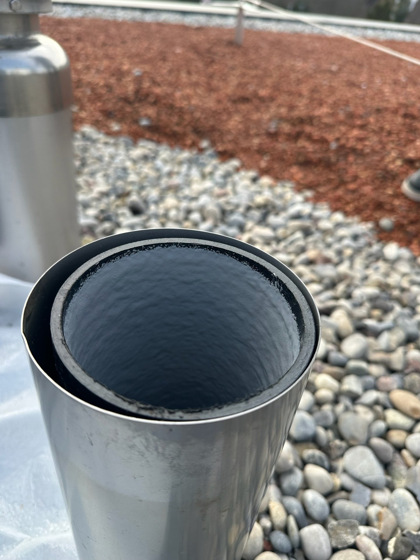 Eines fachgerecht mit Inliner sanierten Edelstahlrohrs mit glatter schwarzer Innenbeschichtung