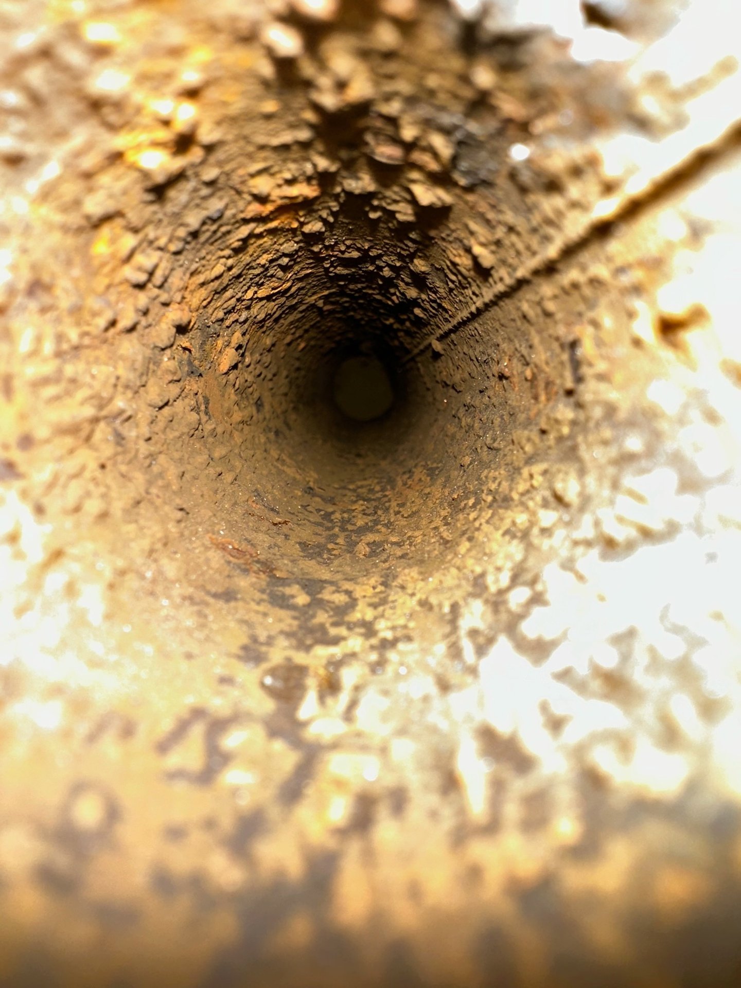 Innenansicht eines stark verrosteten Rohrs mit Ablagerungen und Rissen