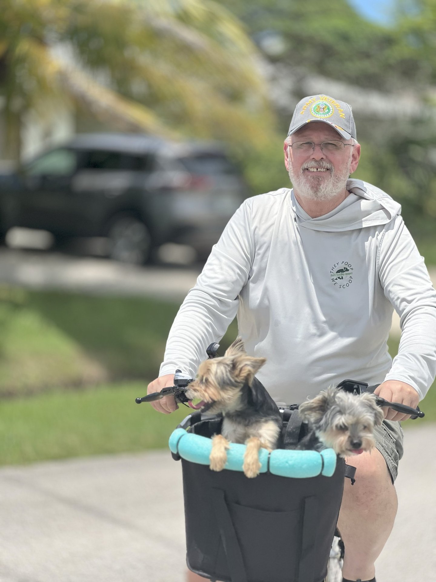 Robert smiling while riding a bicycle with two dogs in a basket