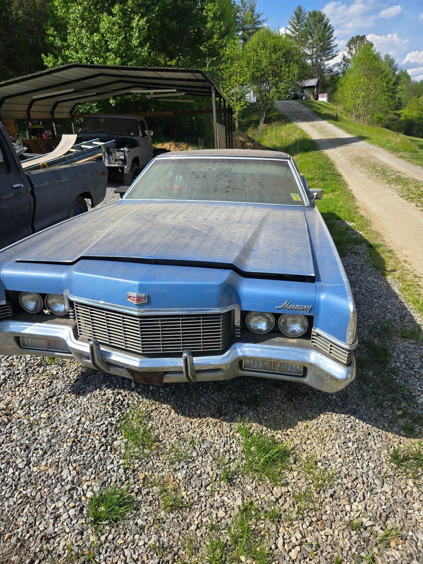 Blue classic car on a gravel driveway