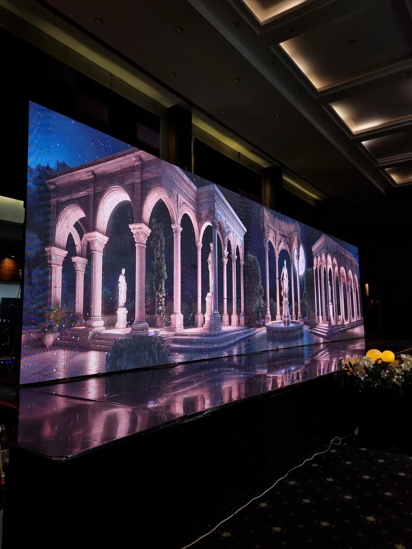 a large led screen of a roman architecture and statues in the middle of a room
