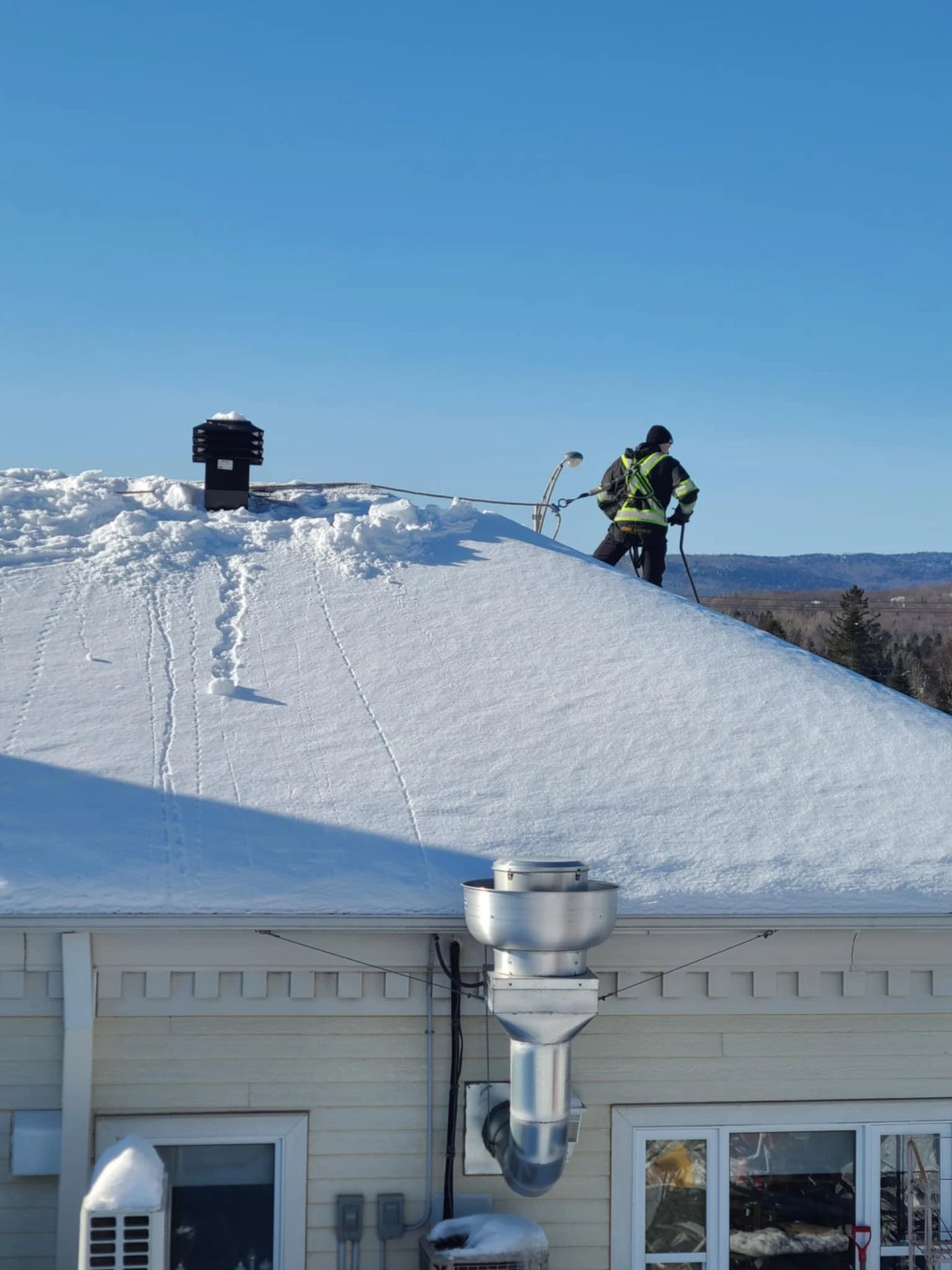 Homme qui déneige toiture avec son harnais (epi)