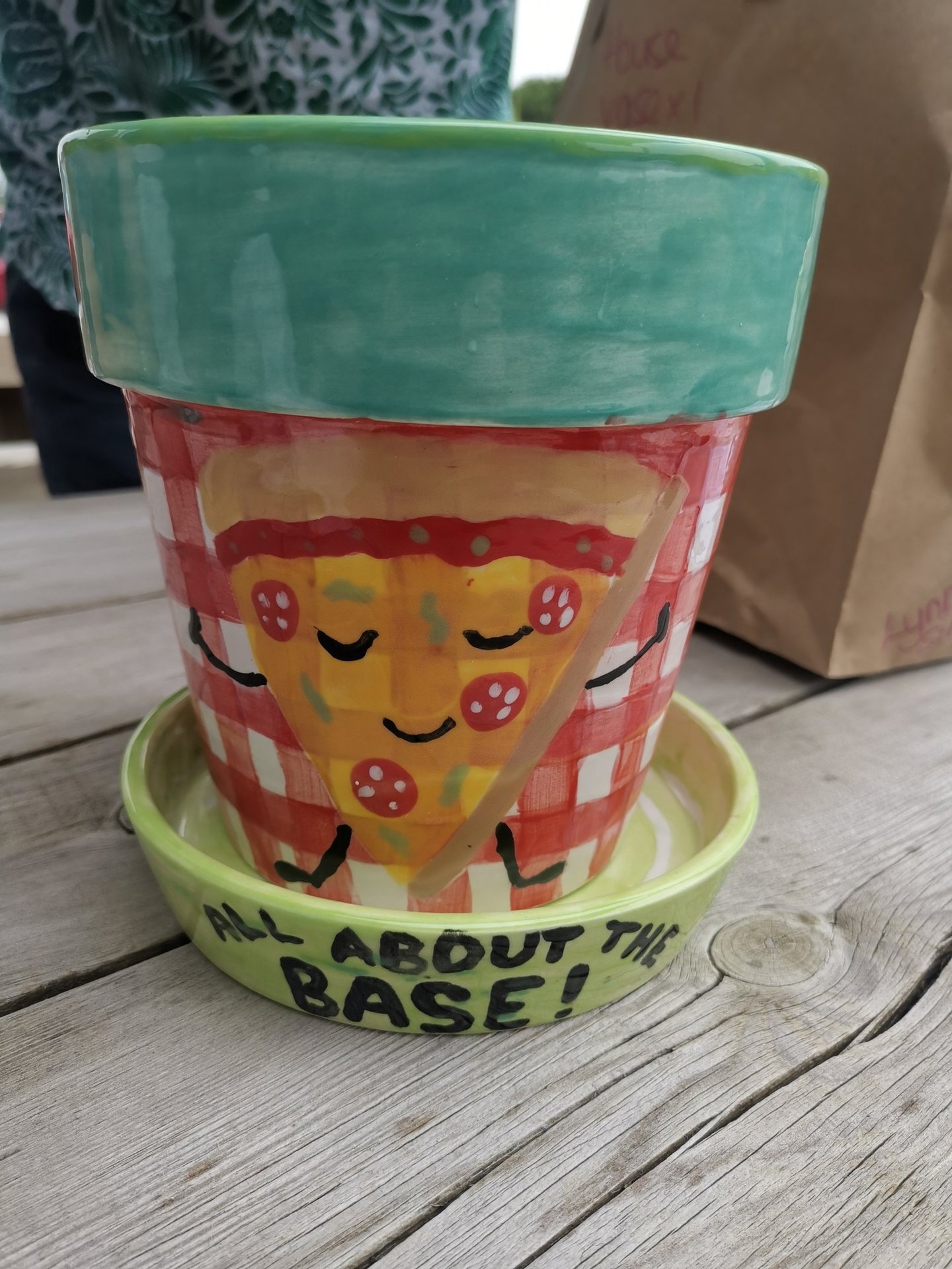 Hand-painted ceramic pizza planter on a wooden table with a smiling pizza slice design.