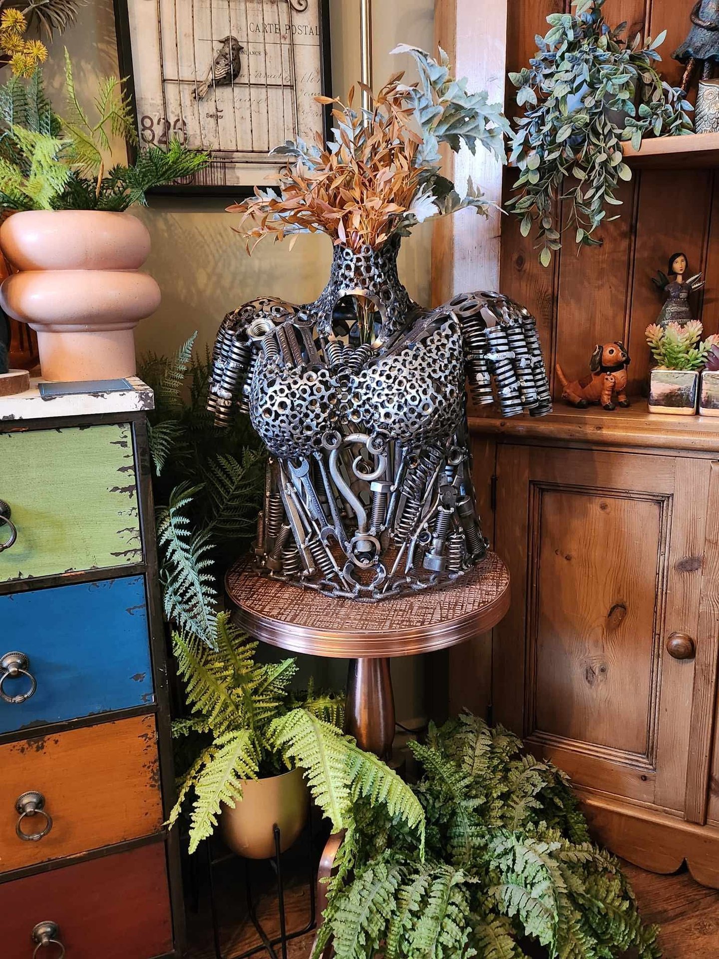 steampunk female torso lifesize bust sculpture made from metal nuts bolts and tools in a rustic room