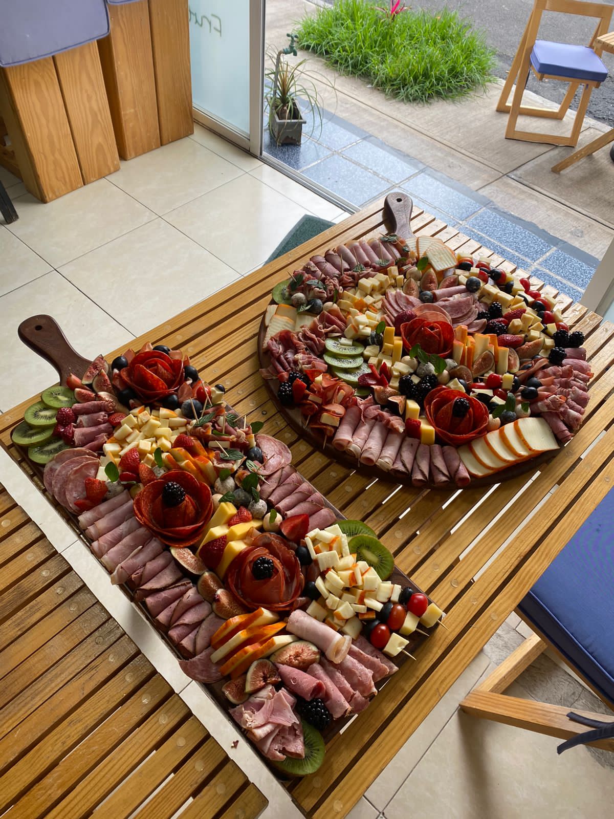 Two large charcuterie and cheese boards beautifully displayed on wooden trays.