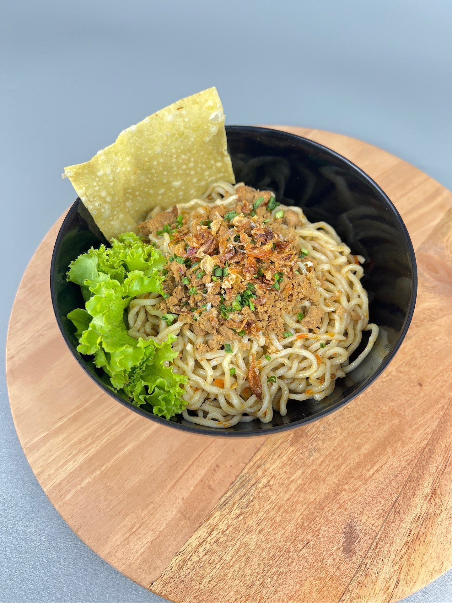 Mangkuk mie ayam dengan topping ayam, daun bawang, dan kerupuk pangsit di Depot Mie Ayam RATU