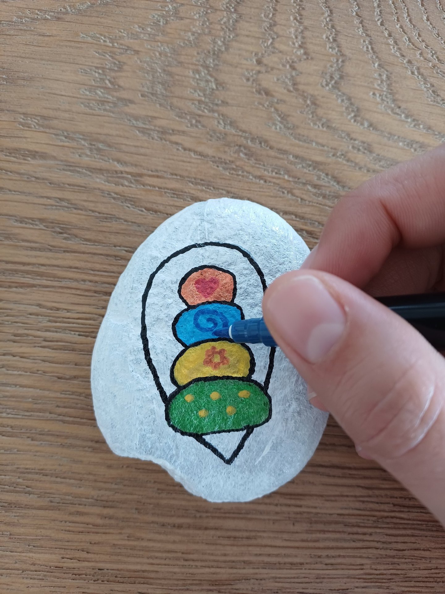 a person's hand holding a pen and drawing on a wanderstone