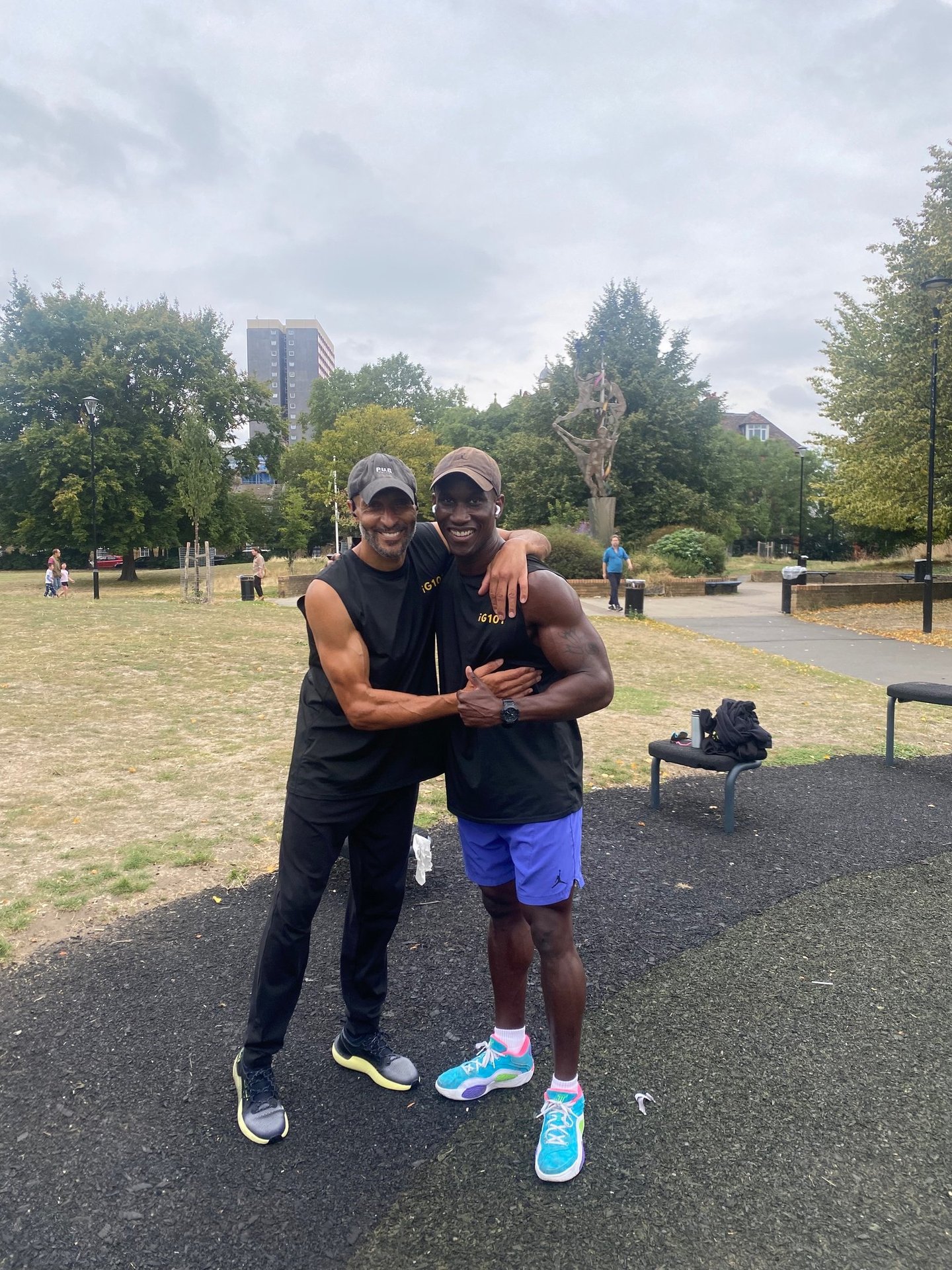 Two athletic men smiling at an outdoor gym park after a fitness workout.