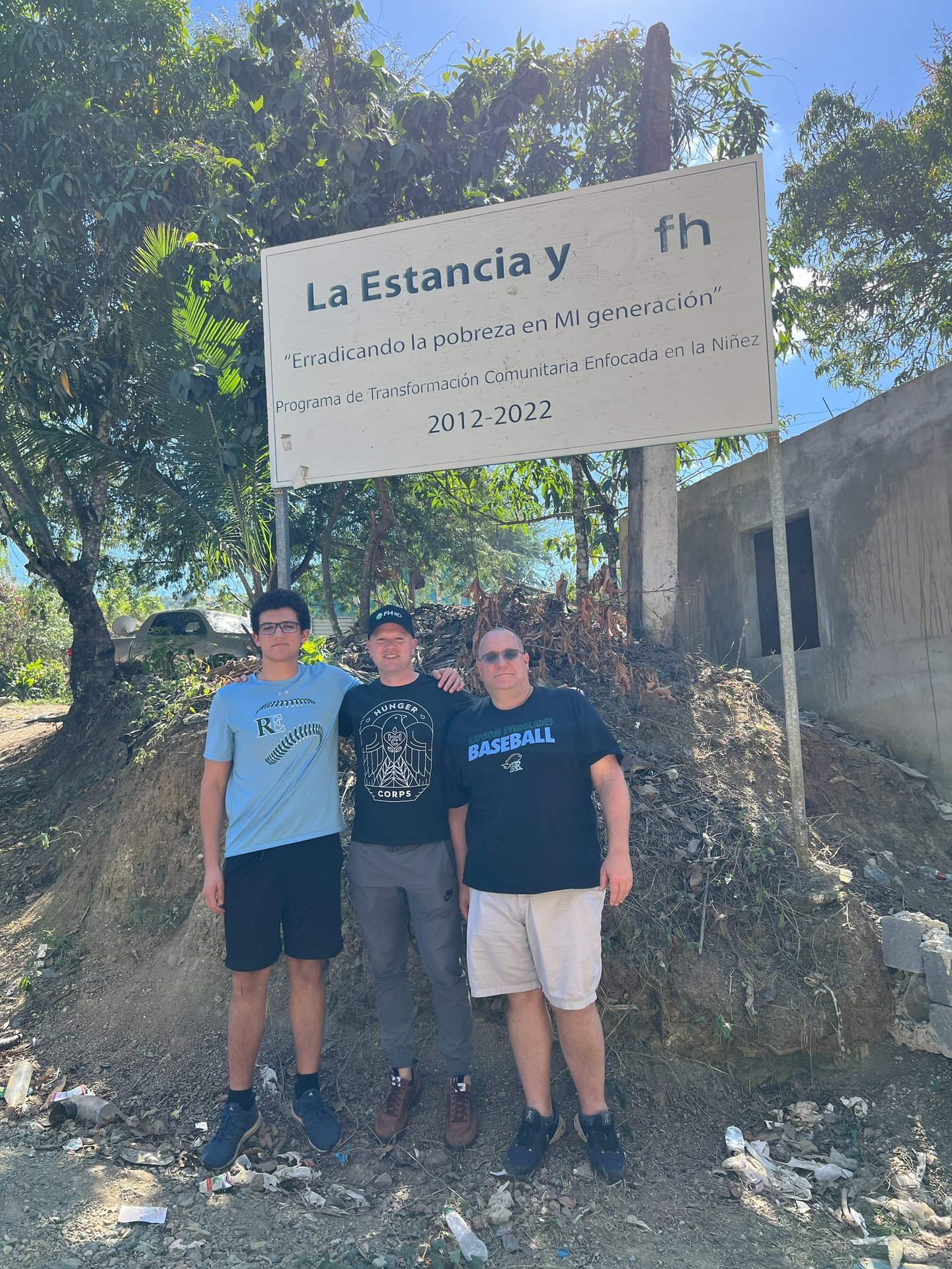 three men standing in front of a sign that says la estrancia y est