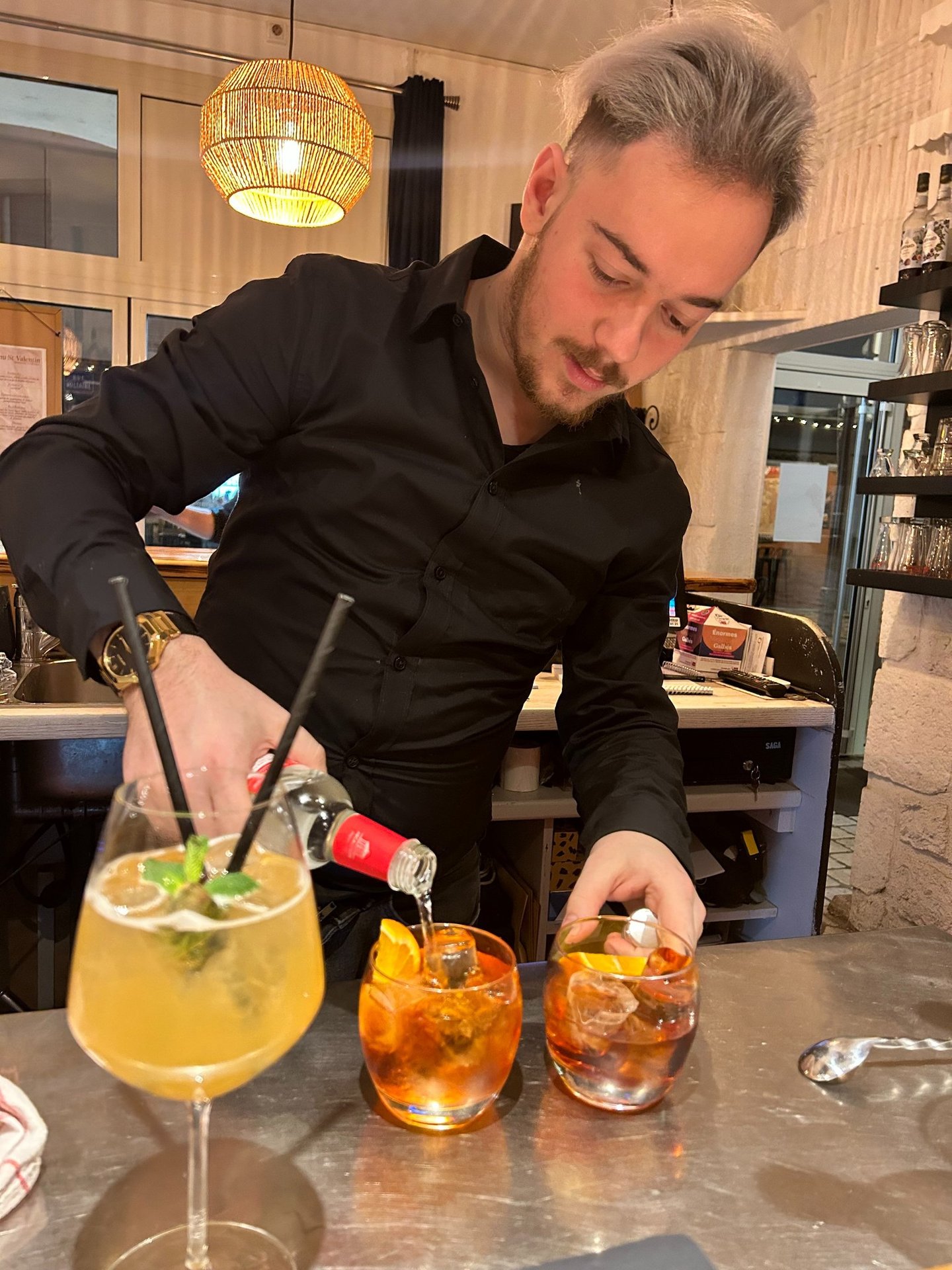 a man in a black shirt is preparing to serve a drink