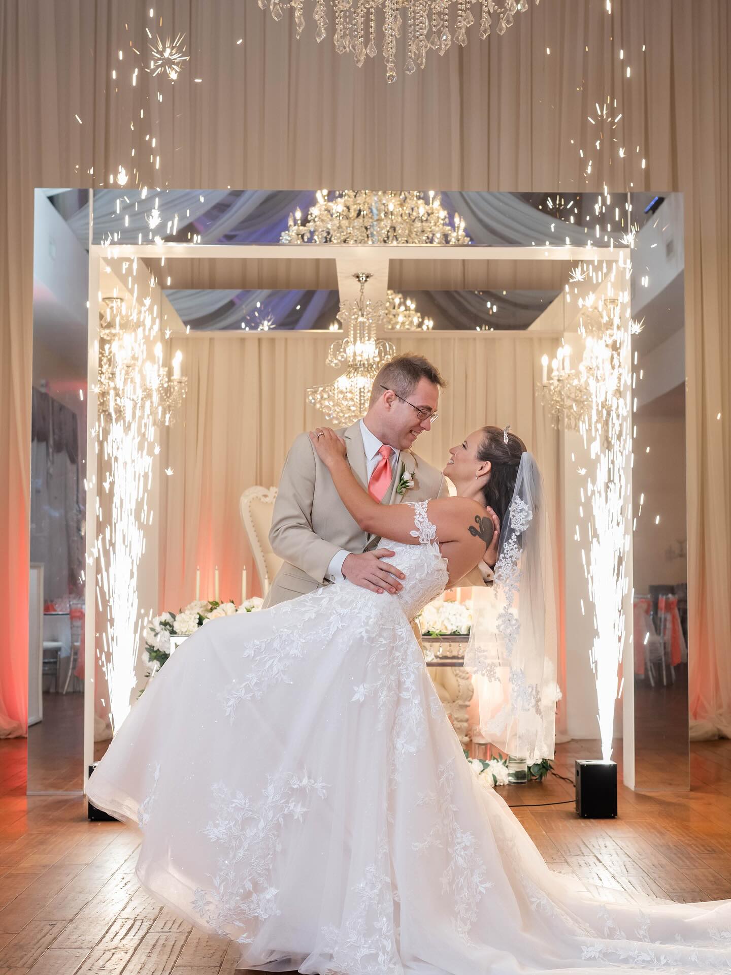 Newlywed couple's first dance featuring indoor sparkler fountains and elegant chandeliers.