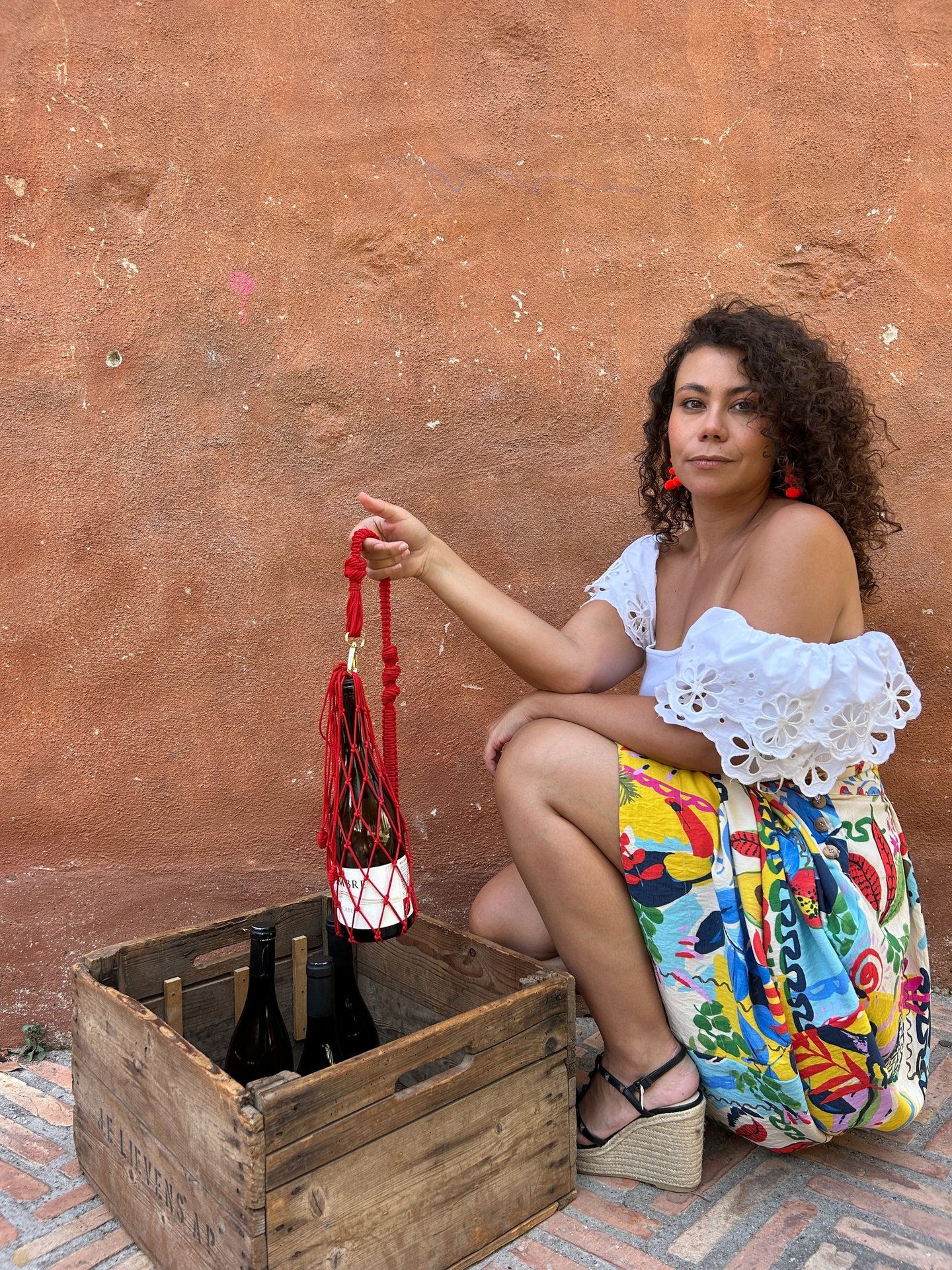 chica con una porta bolsa para el vino. Se ve la botella del vino también y la modelo esta agachada 