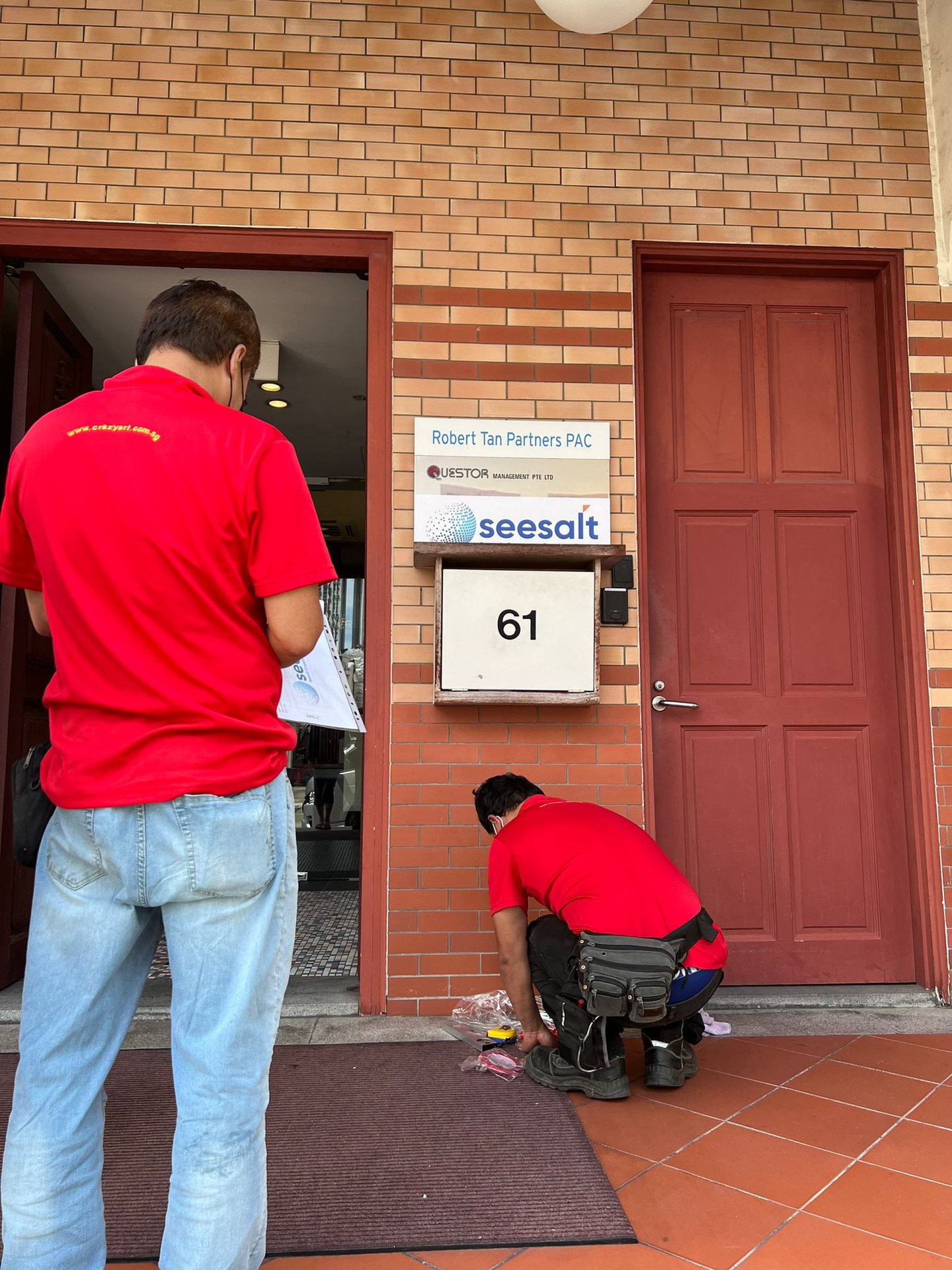 Couple of workers installing SeeSalt logo alongside Questor Management