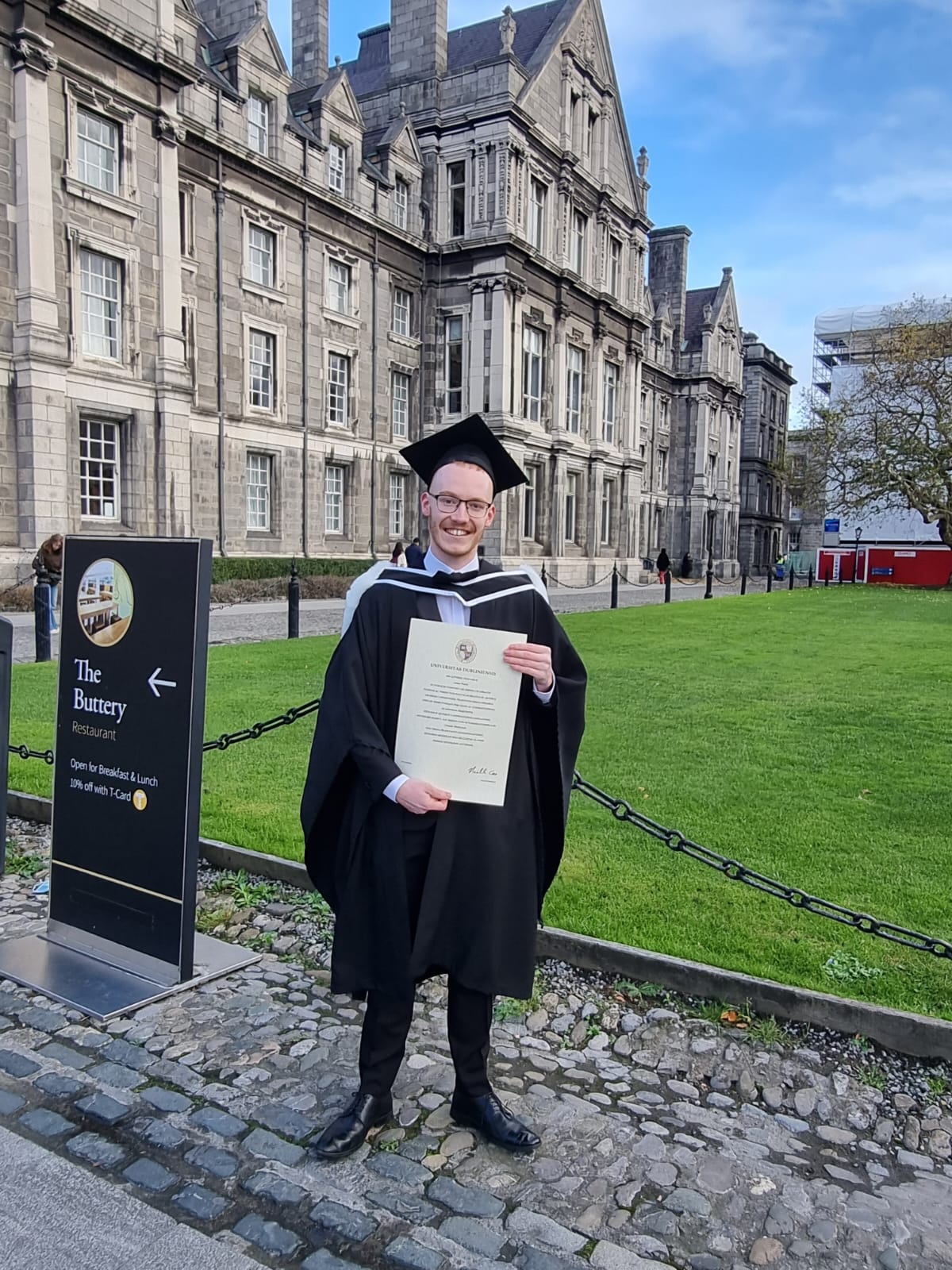 a man in a graduation gown holding a diploma certificate