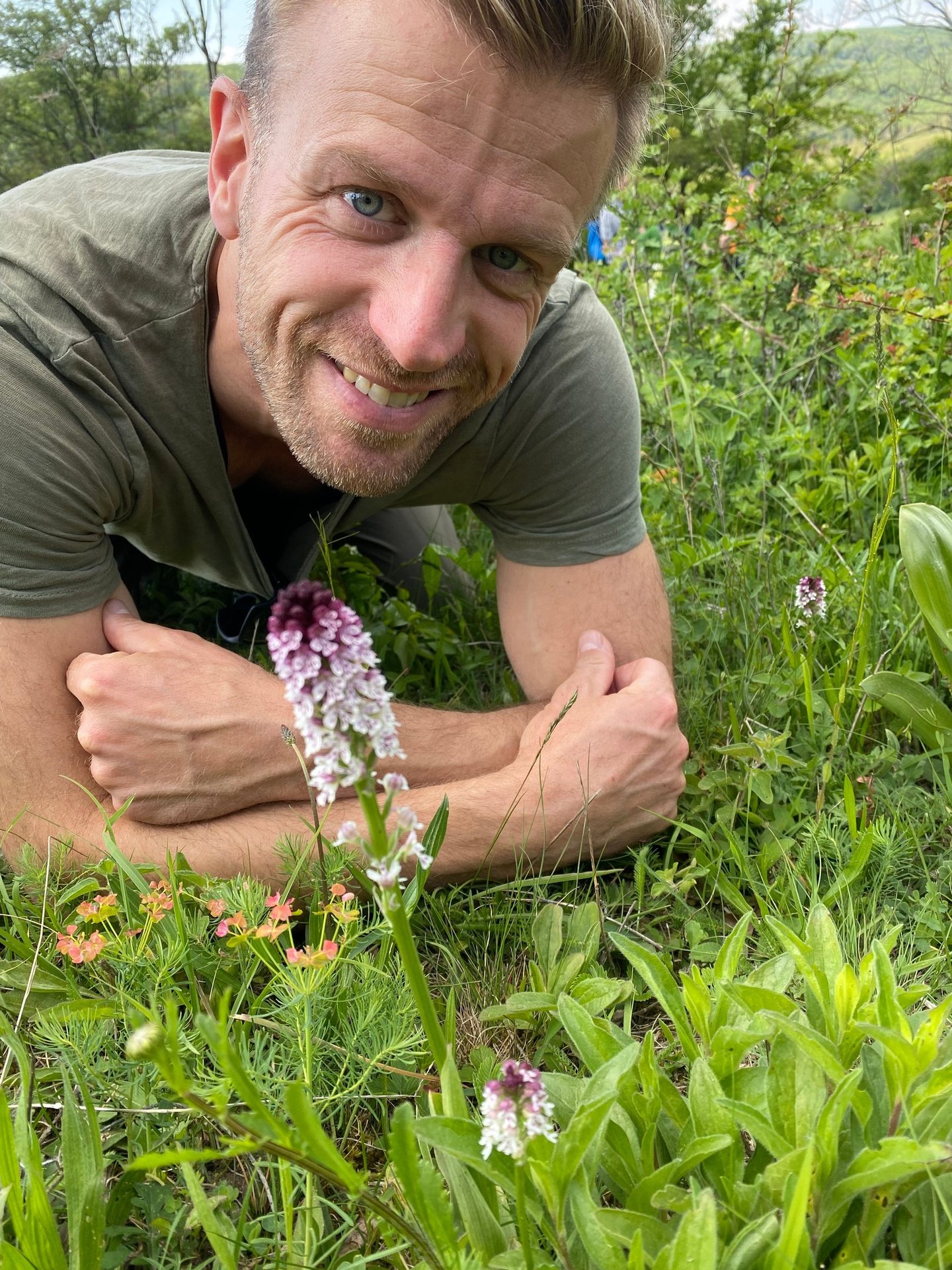 Sebastian Brandt liegt auf einer Wiese und hat vor sich ein Brandt Knabenkraut.