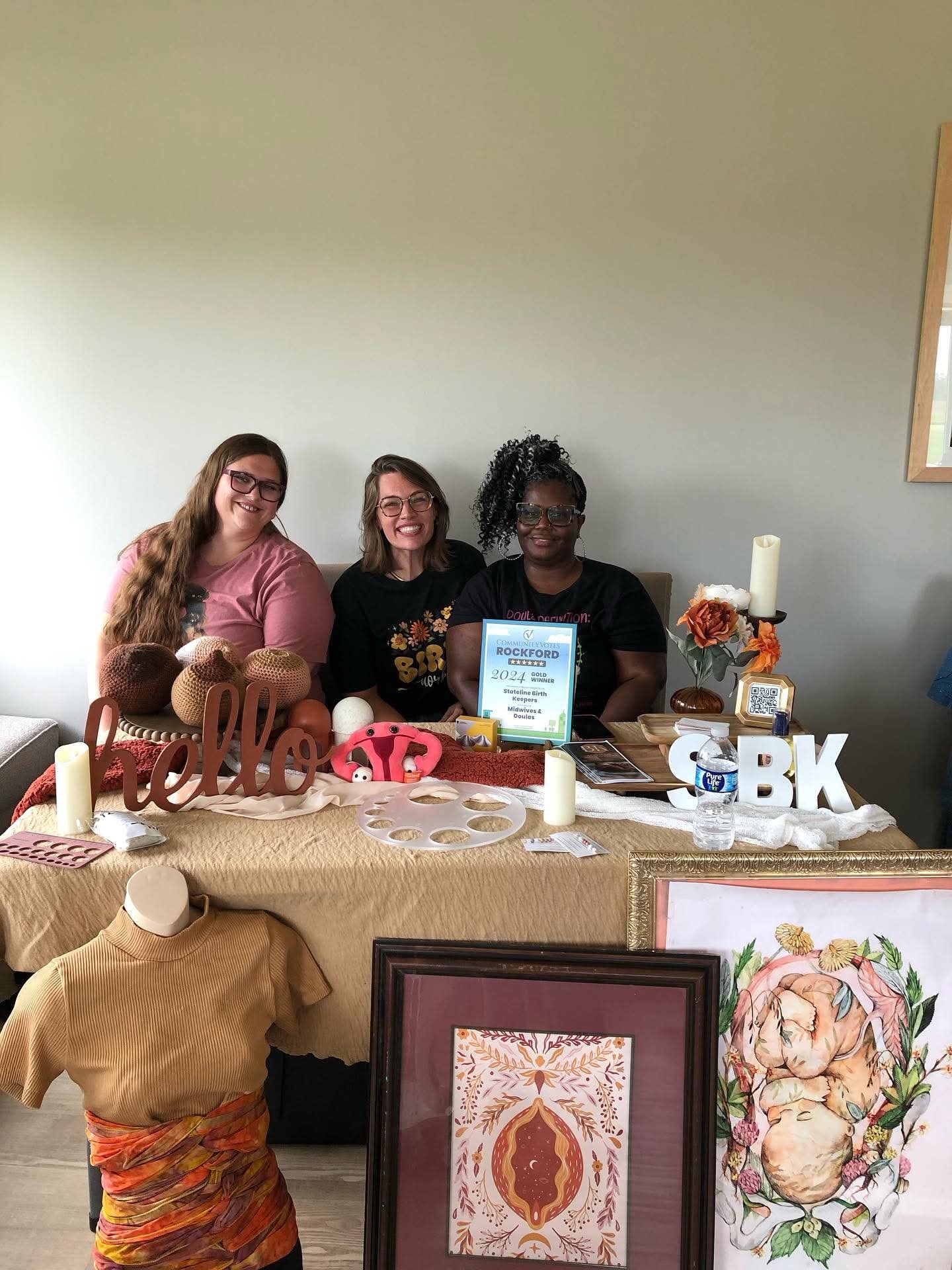 a group of women sitting at a table with doula items around them