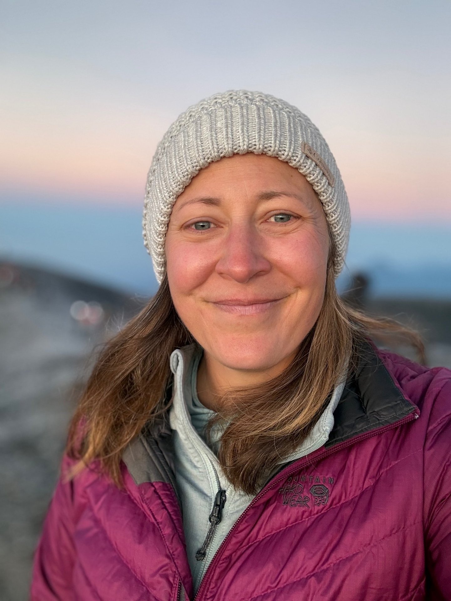 a woman in a purple jacket and a white hat
