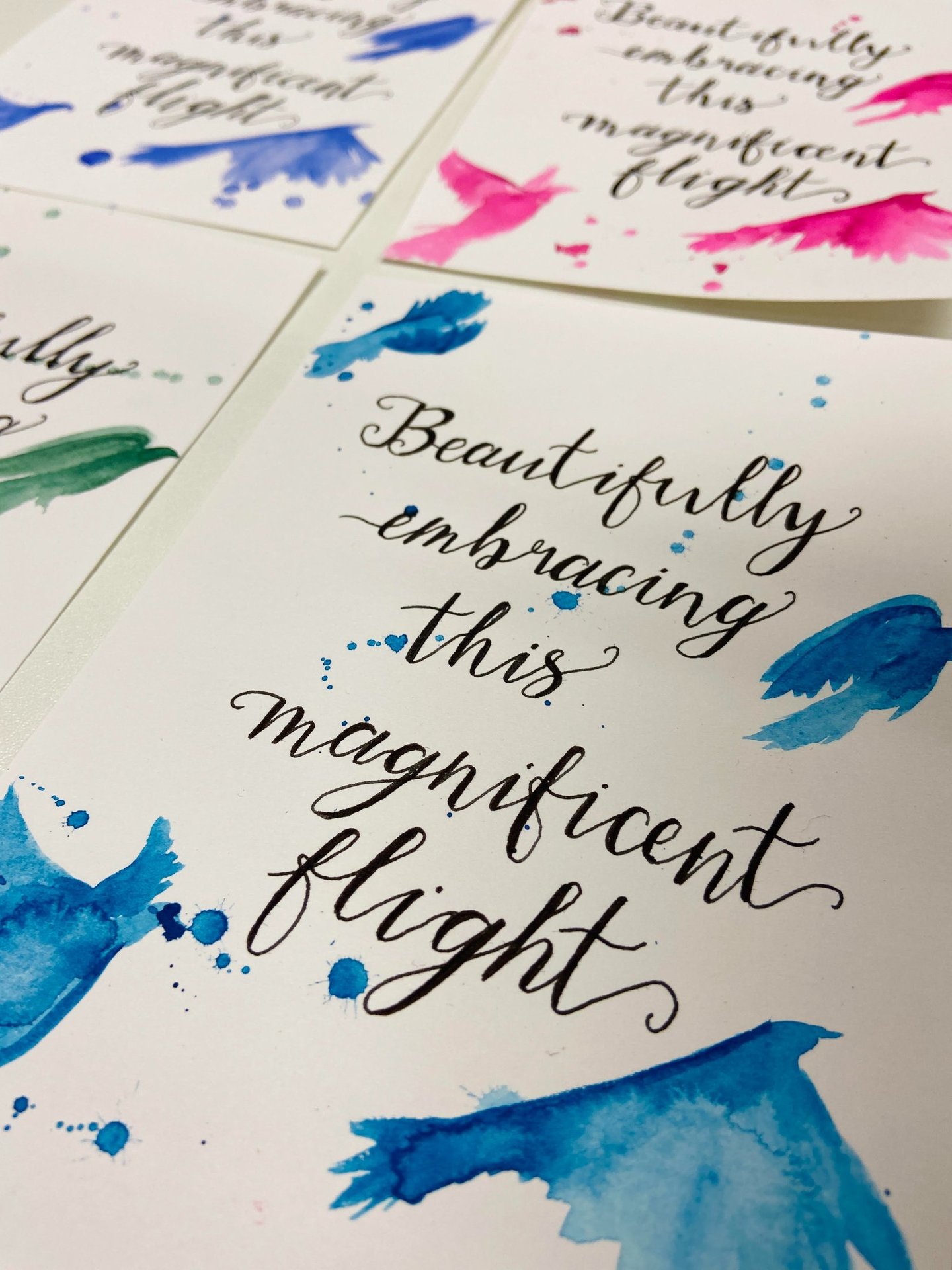calligraphy lettering in black ink on a white background with blue painted birds