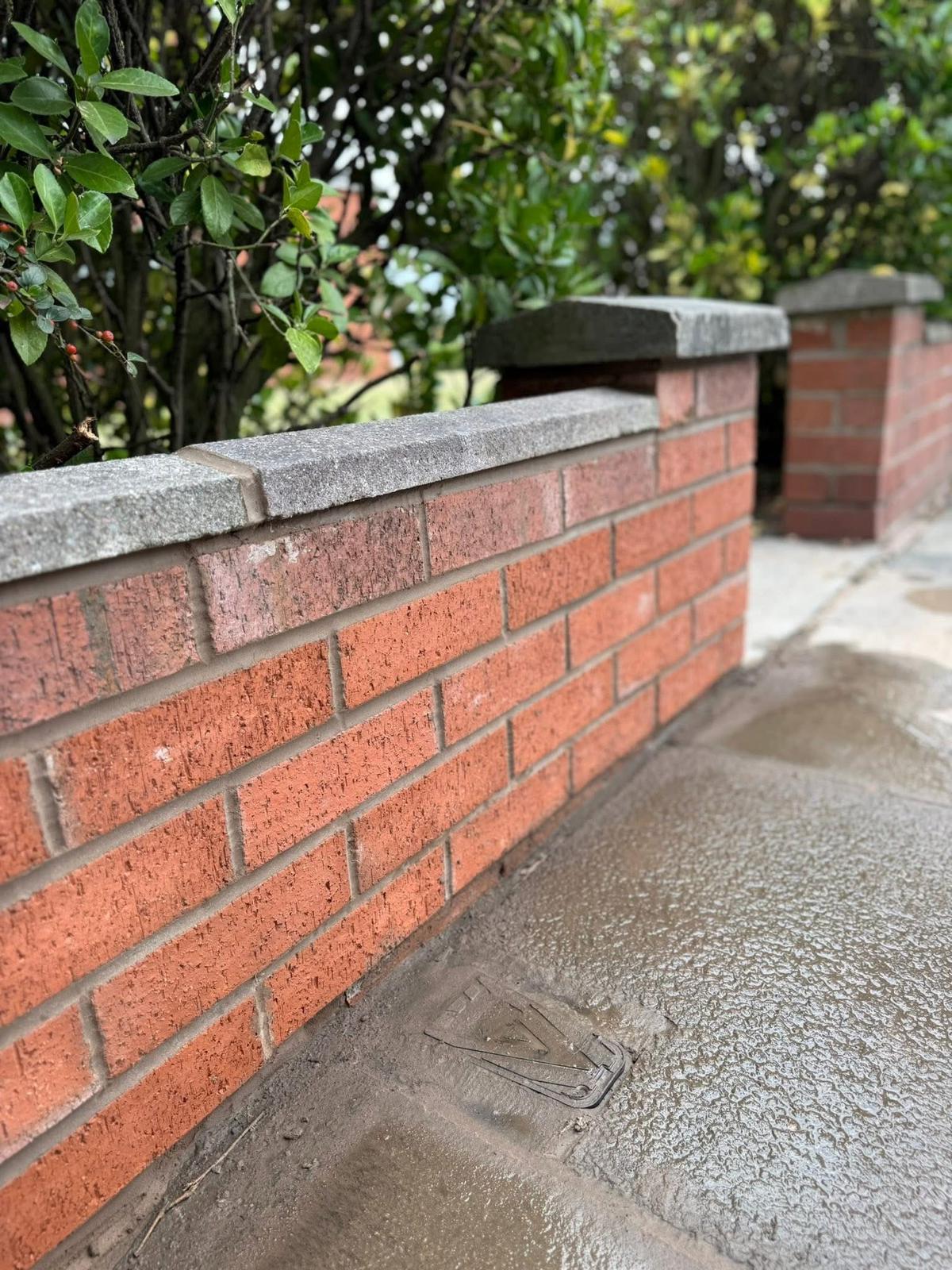 A red brick garden wall with a grey stone coping finish in Southport