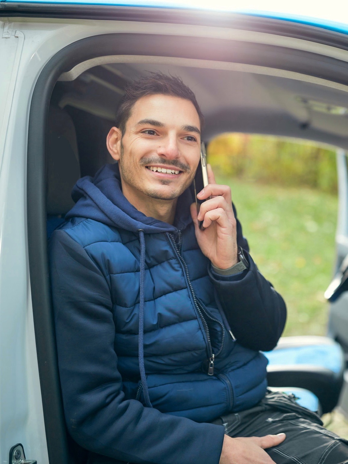 a man in a blue jacket is talking on a cell phone