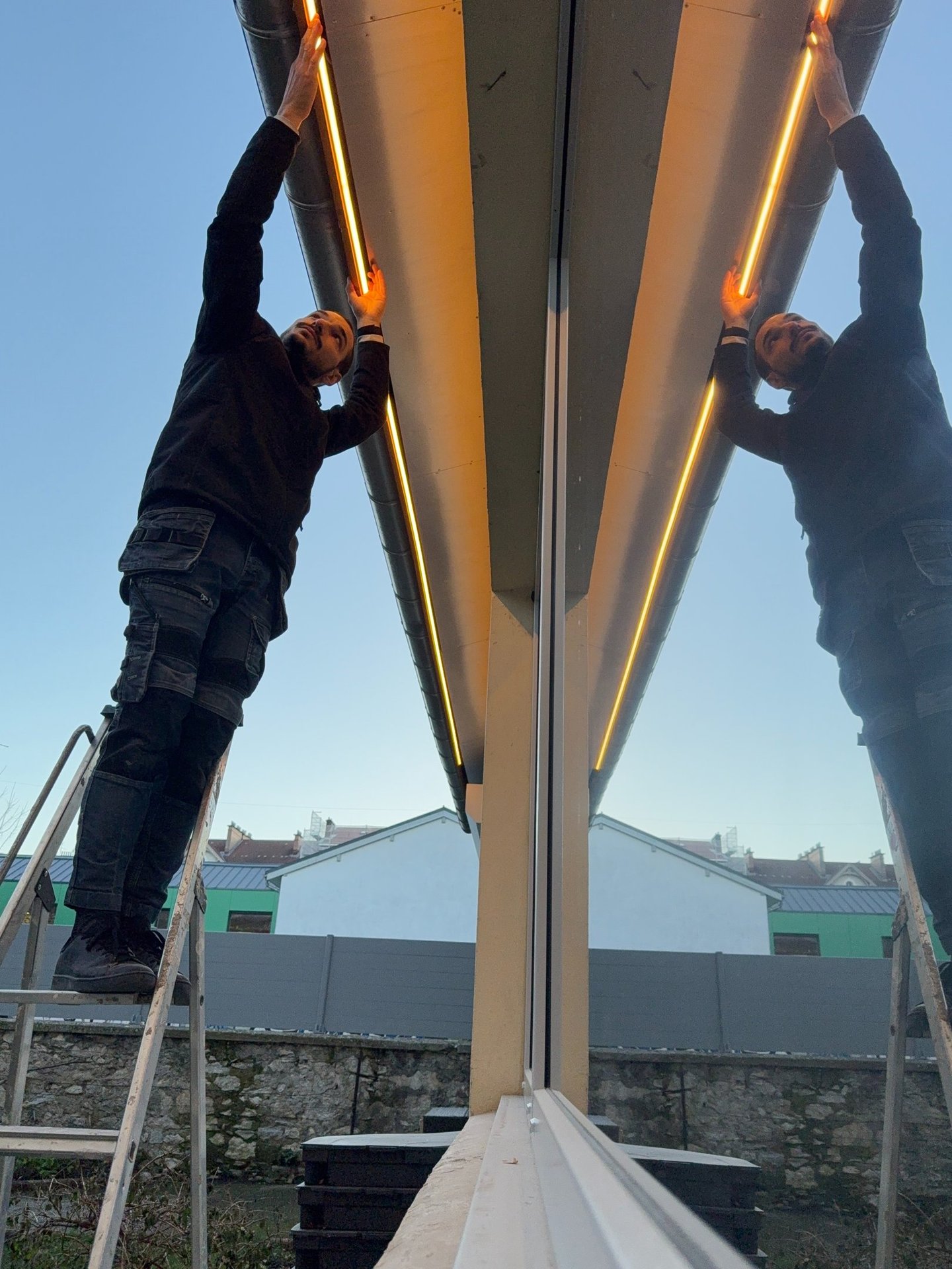 two men standing on a ladder ladder to reach up to the top of a building