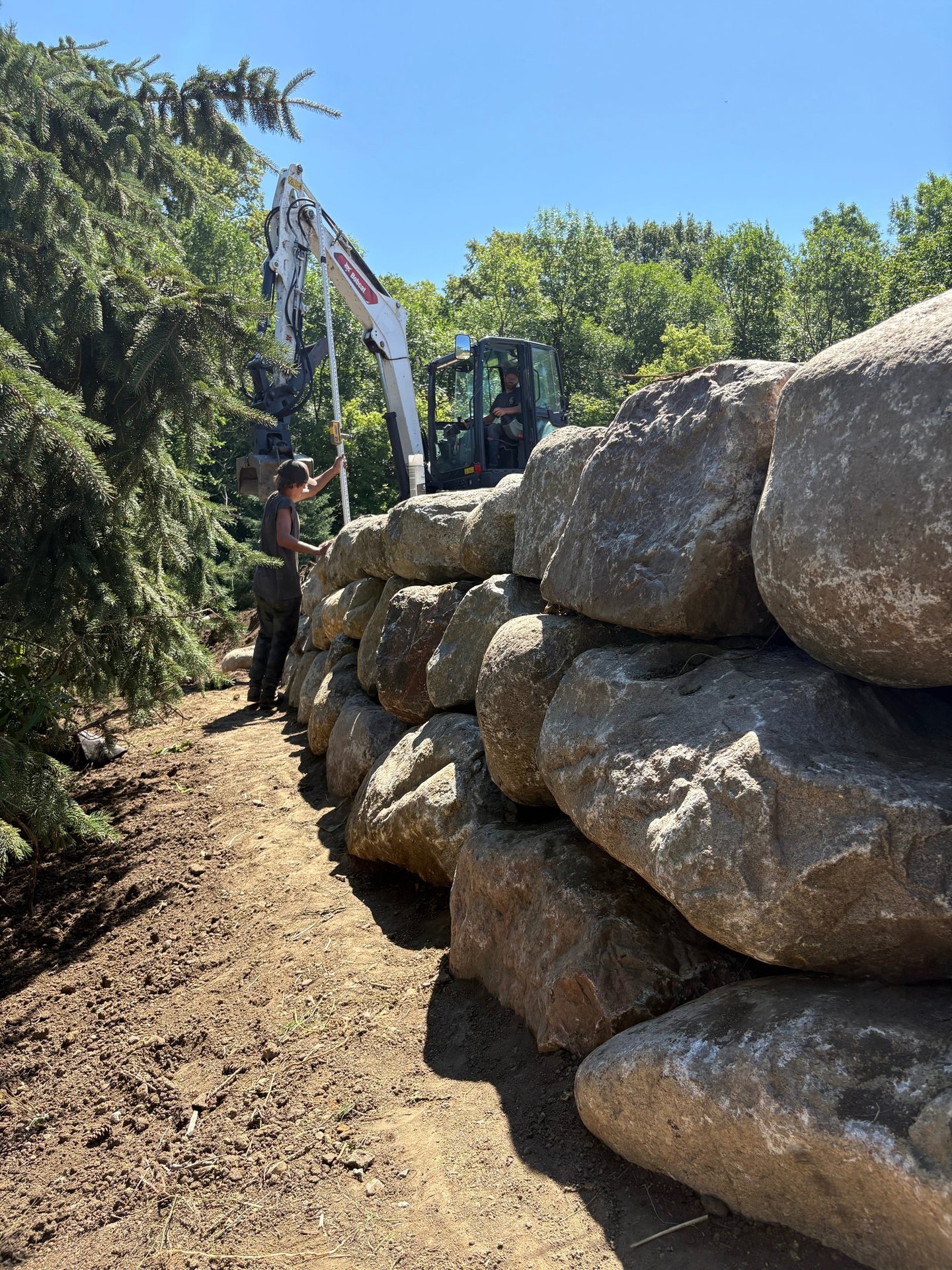 Boulder wall being checked for proper level