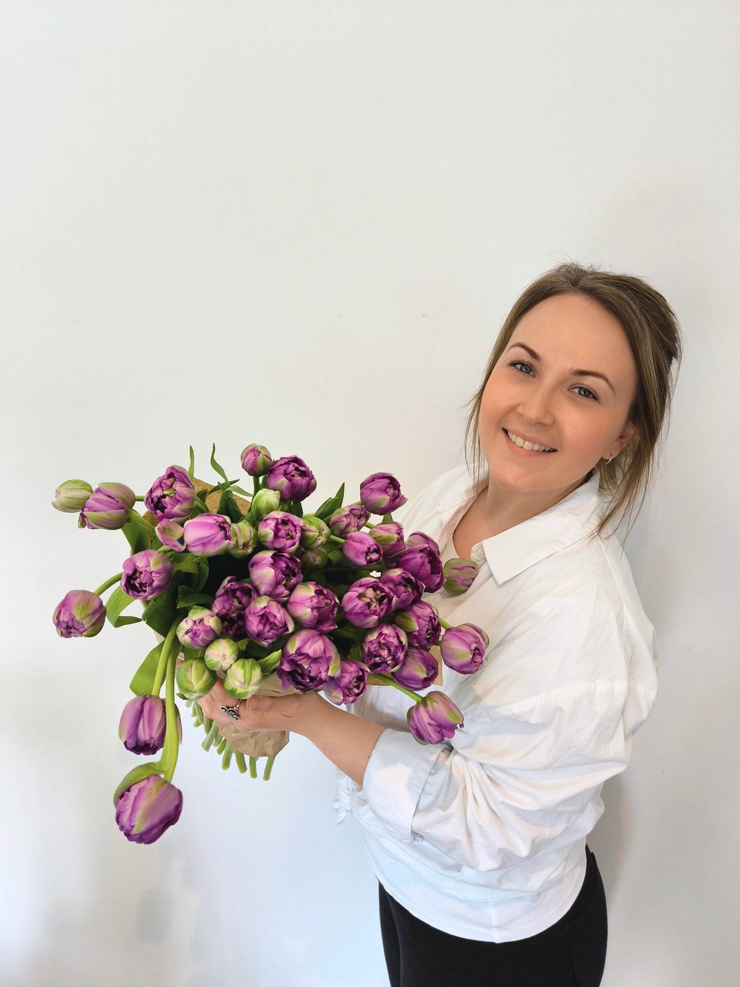 female florist holding bouquet of purple tulips