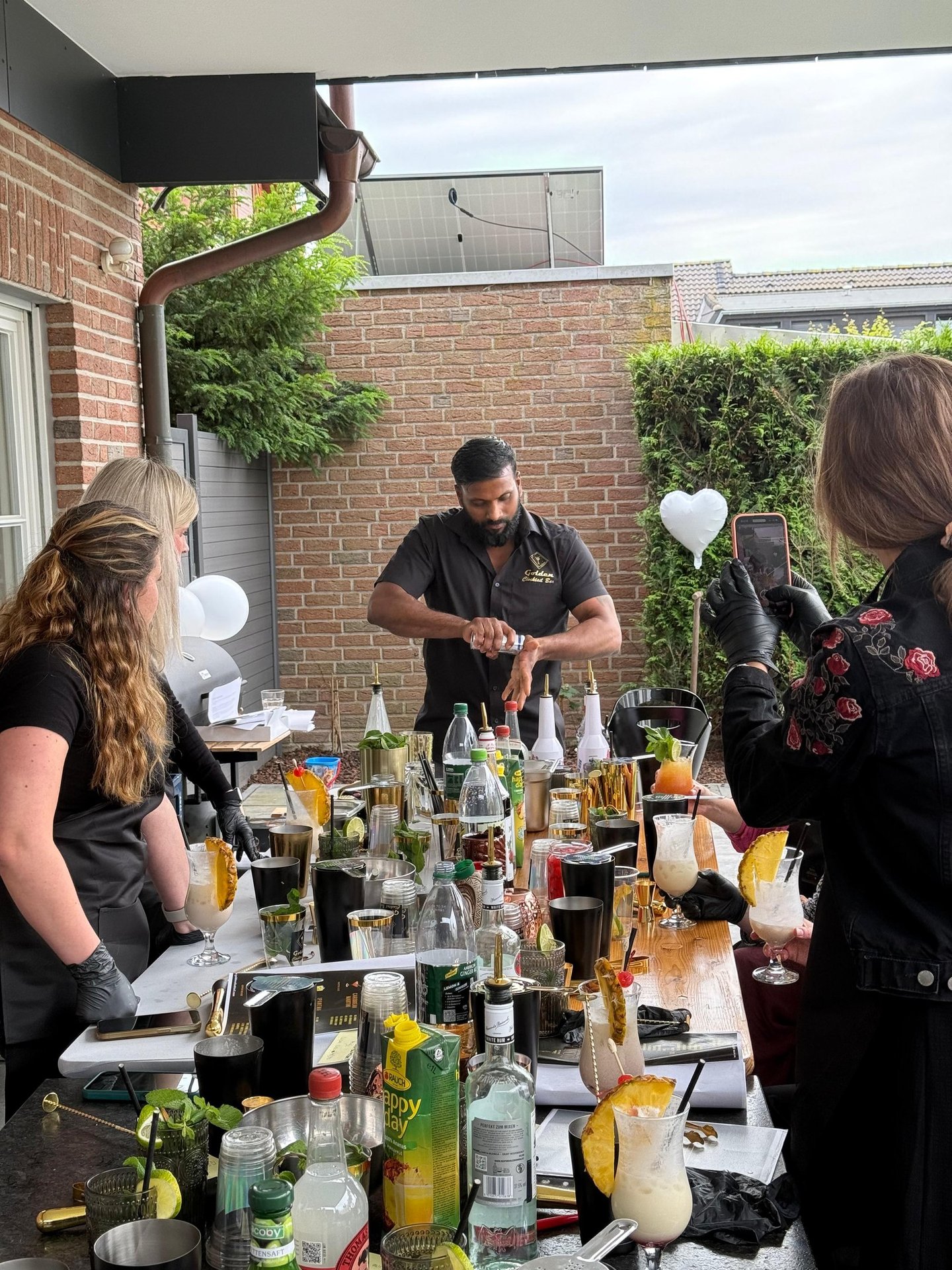 Professional mixologist at an outdoor mobile bar preparing cocktails for guests at a private event.