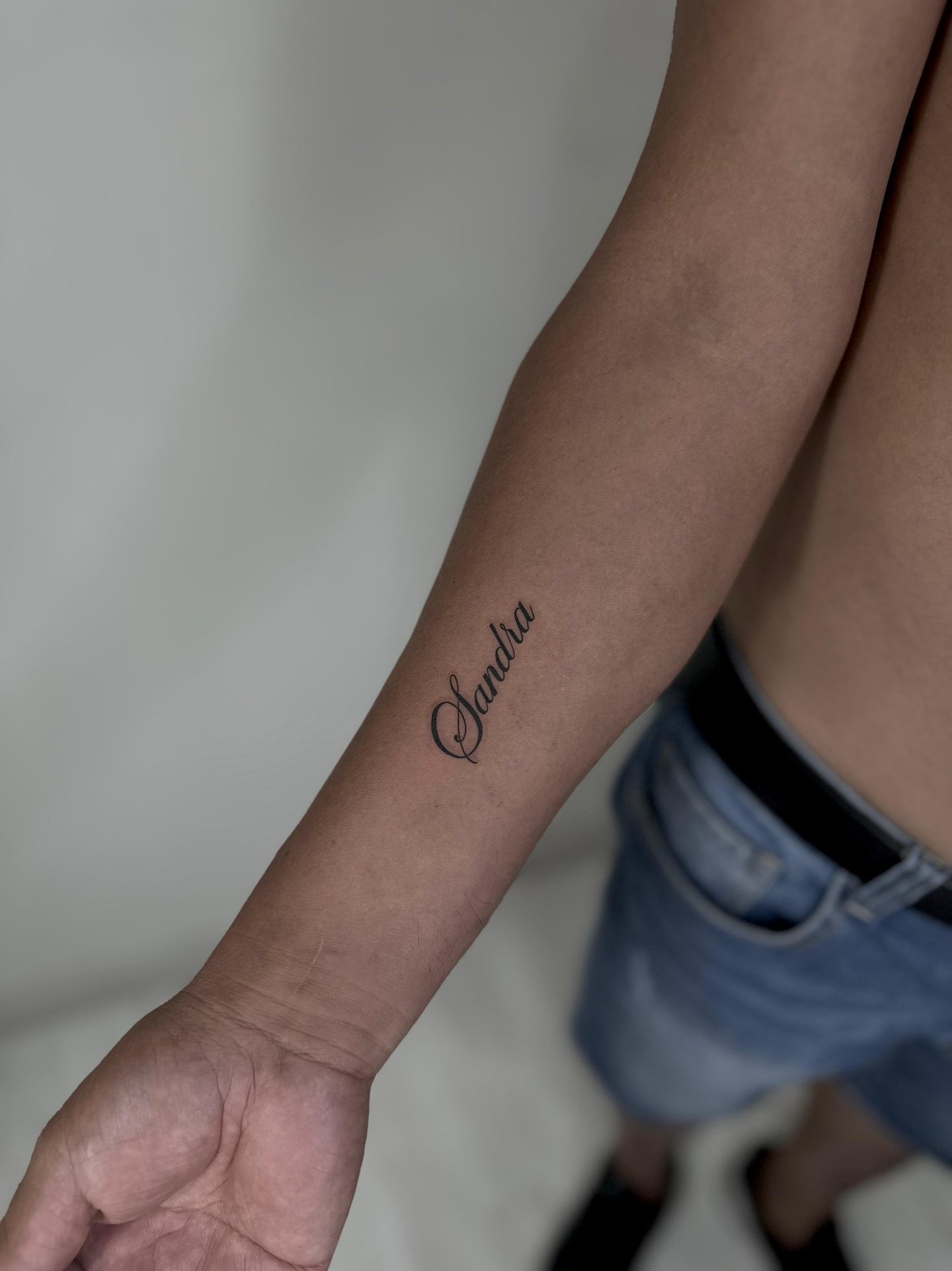 Tatuaje fineline en Madrid de nombre en caligrafía cursiva elegante en el antebrazo