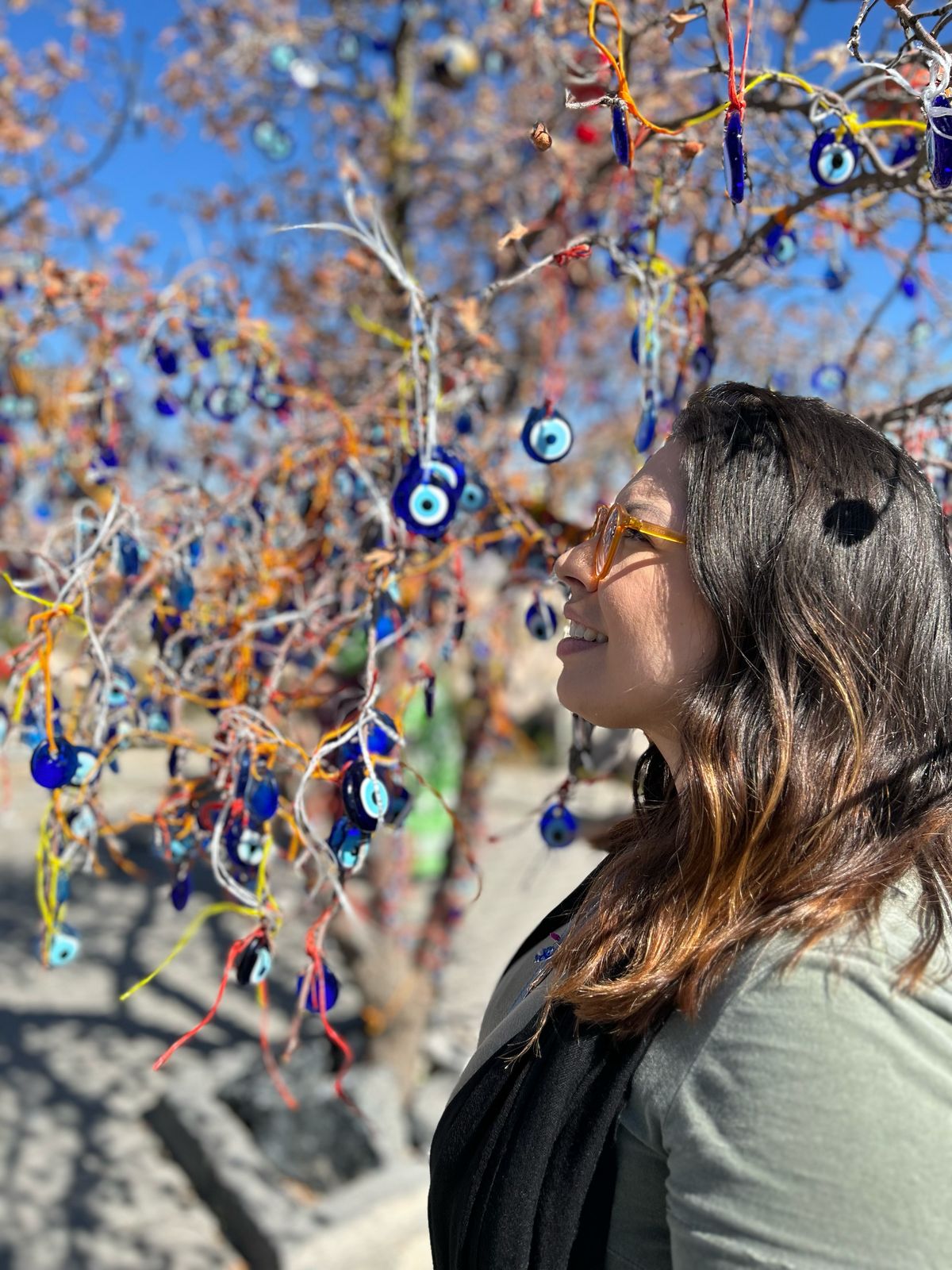 Uma mulher de perfil ao lado de uma árvore com enfeites na Turquia