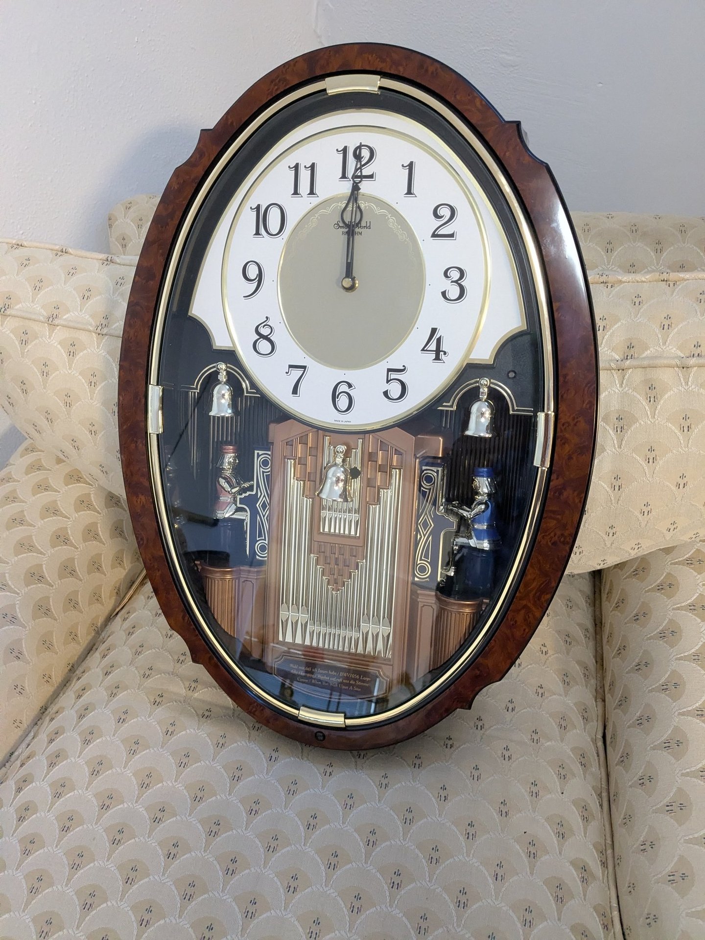 Vintage Small World Rhythm musical wall clock with wood grain frame and rotating pendulum figures.