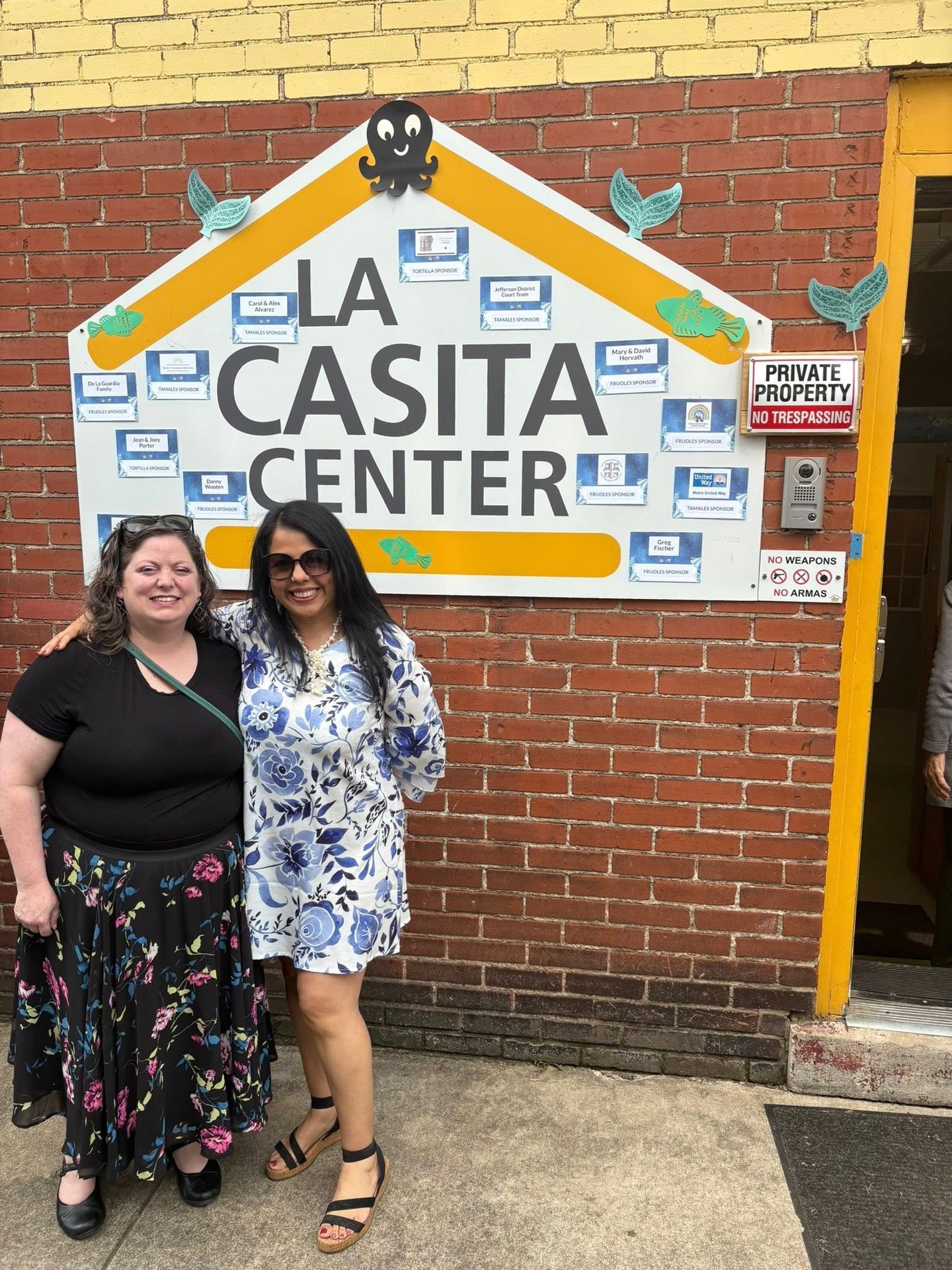 Two women standing in front of the La Casita Center building signage