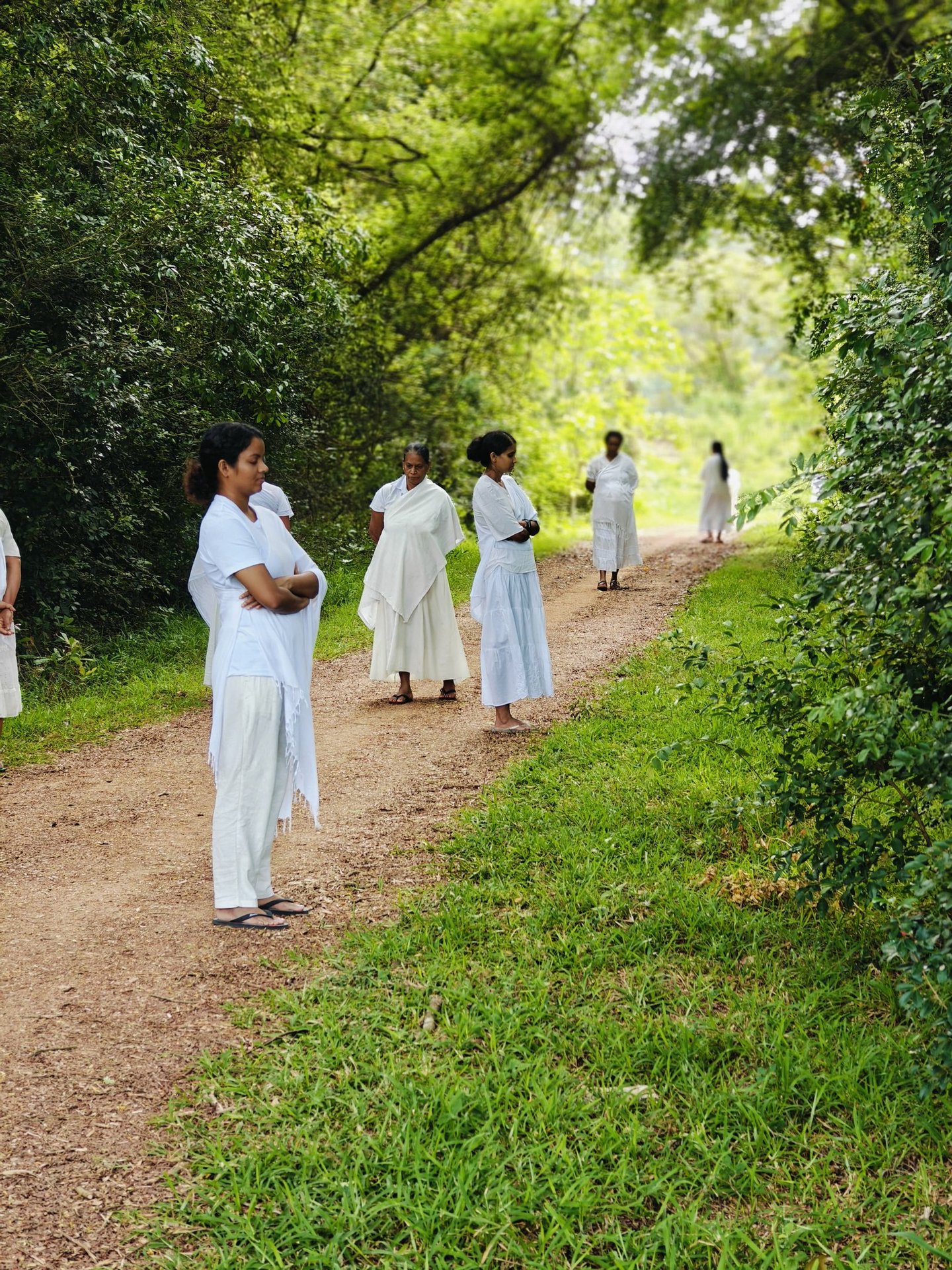a group of people in white dresses walking down a path