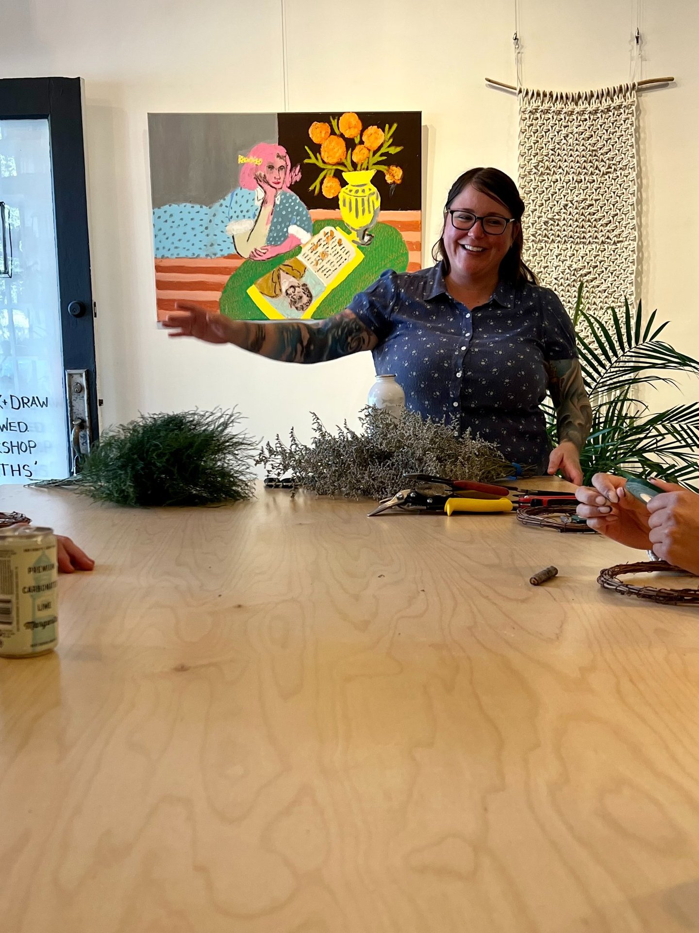 a woman is standing in front of a table with wreath making materials on it