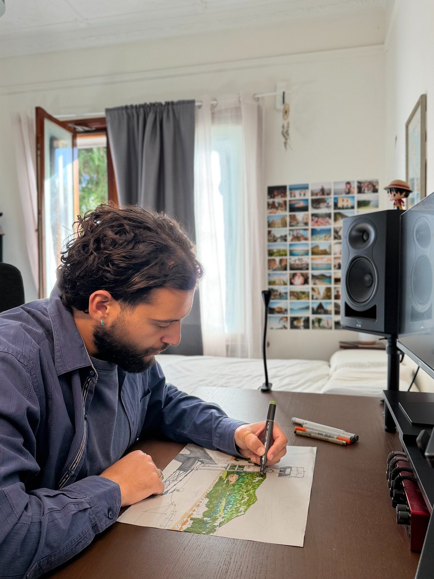 A creative artist sketching a colorful architectural landscape with markers at a studio desk.