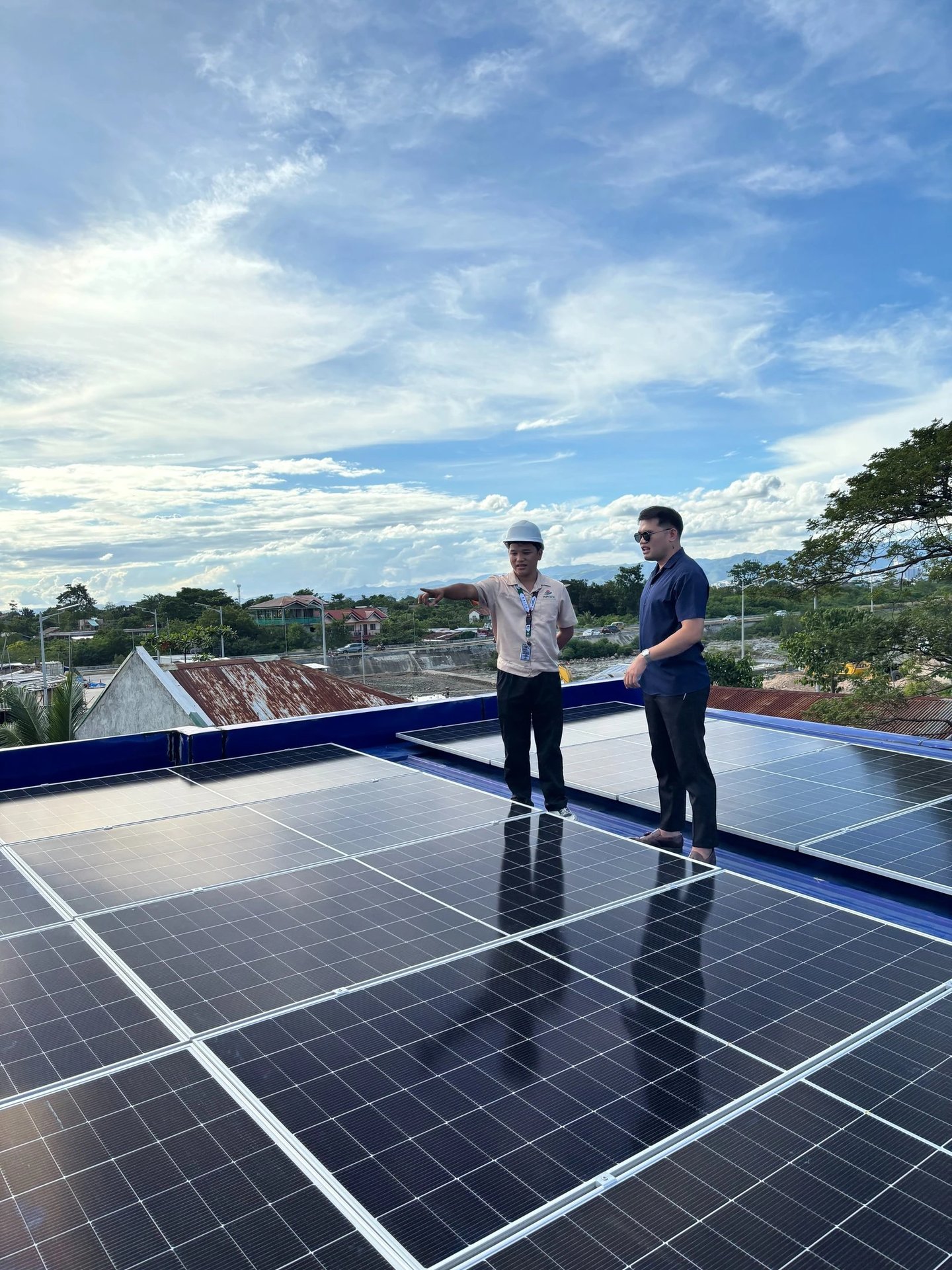 An engineer and client inspecting a residential rooftop solar panel installation under a blue sky.