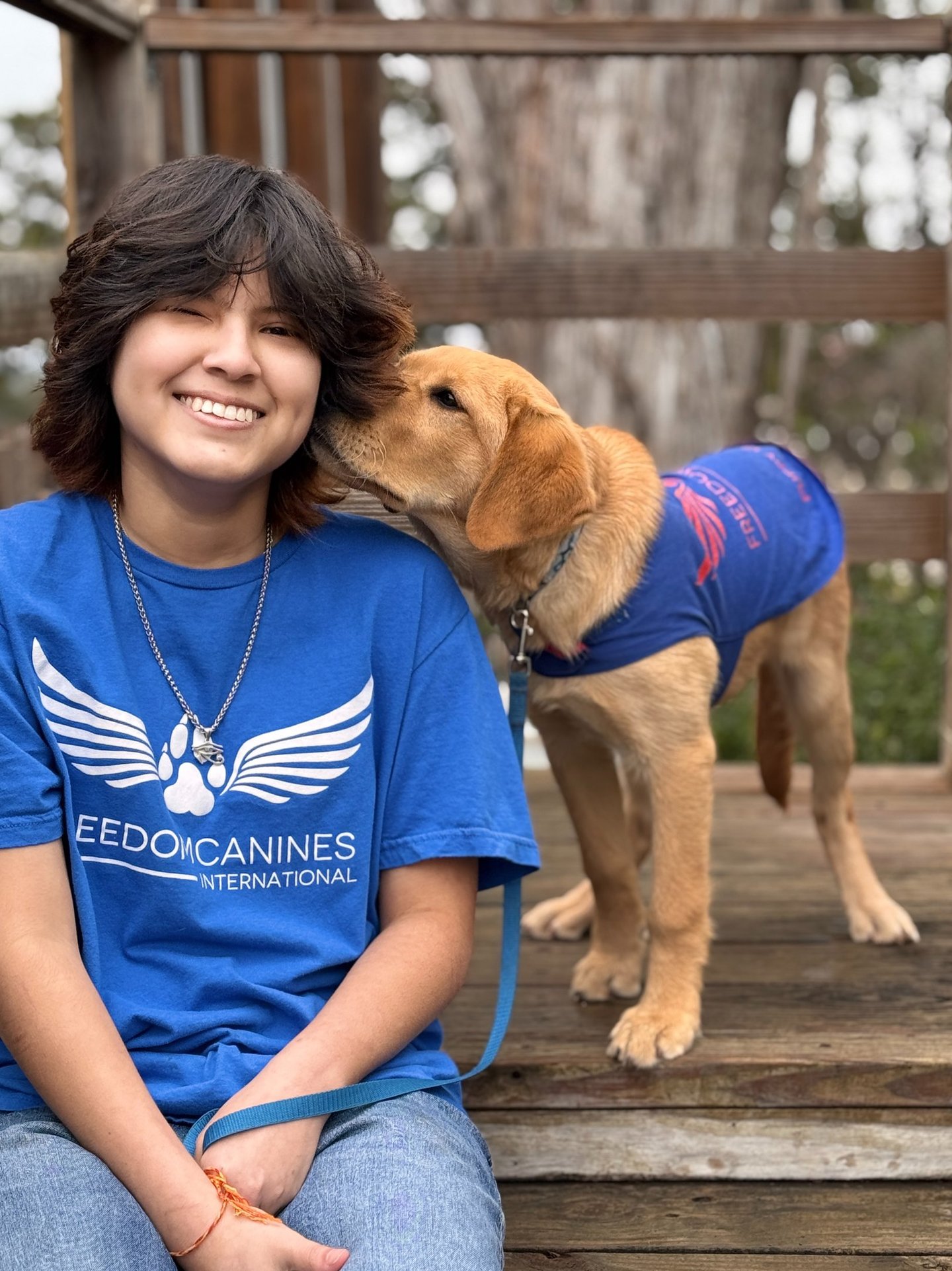 A cute puppy nuzzles his puppy raisers ear while she smiles